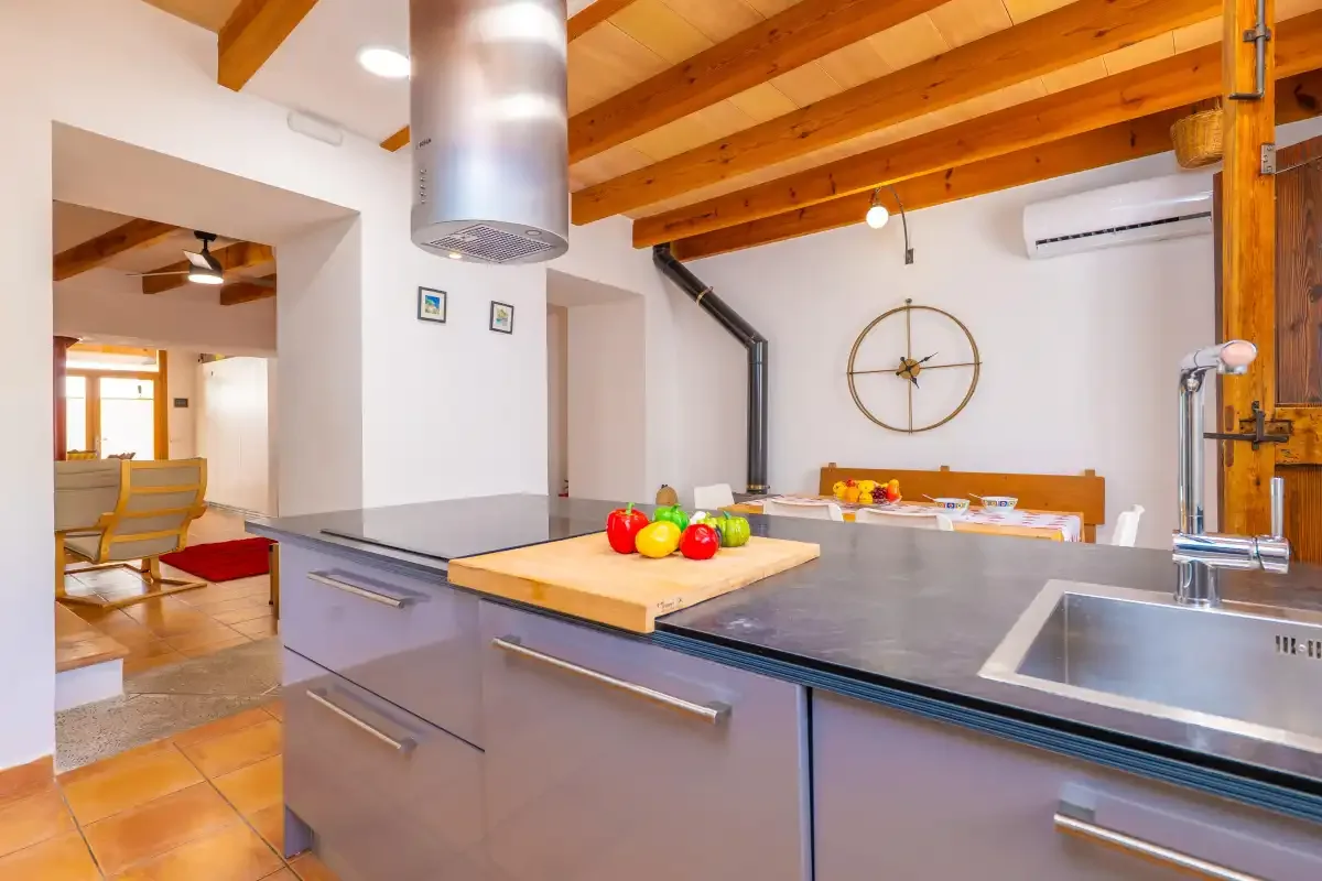Una cocina con una amplia encimera y una mesa de comedor bajo vigas de madera vistas.