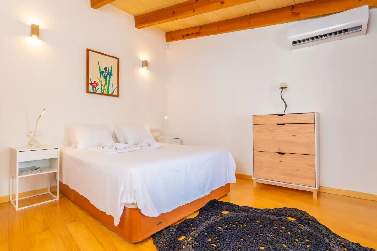 Un dormitorio con una cama, vigas de madera en el techo y una cómoda.