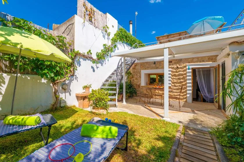 Un patio soleado con asientos, una cubierta de sombra y un pequeño jardín.