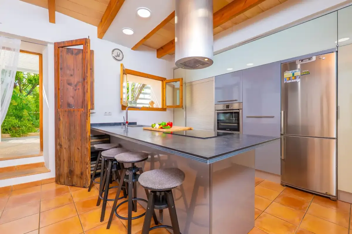 Una cocina moderna con una isla amplia, asientos de barra y electrodomésticos de acero inoxidable.