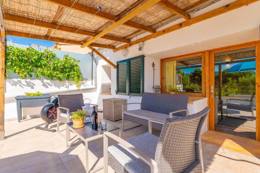 Una zona exterior cubierta con muebles de mimbre y un árbol frondoso.
