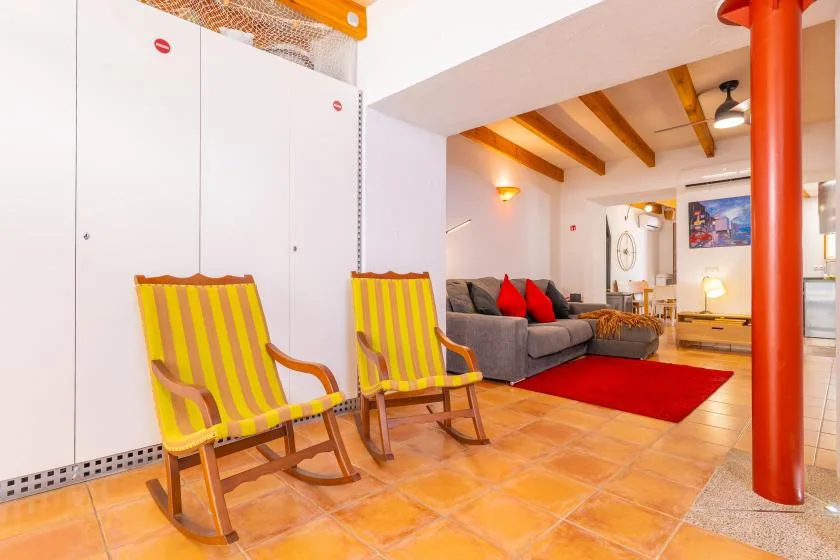 Una sala luminosa con asientos a rayas y un sofá gris bajo vigas vistas.
