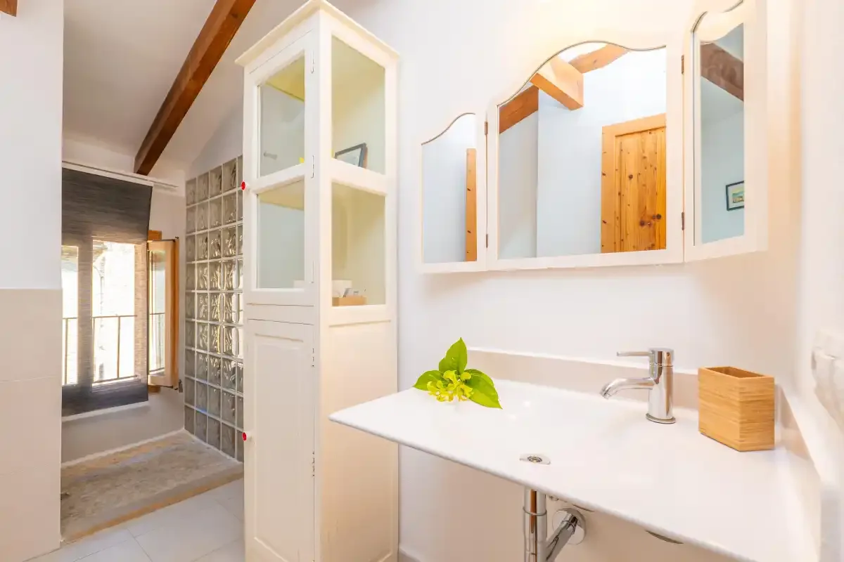 Un lavabo de baño luminoso está junto a una pared de bloques de vidrio.
