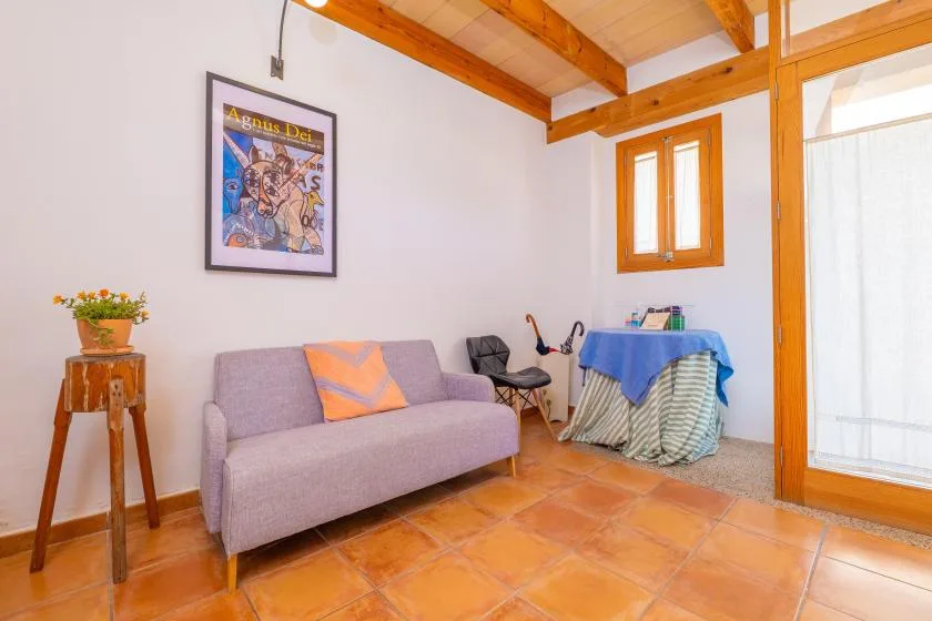 Una luminosa zona de estar tiene un sofá, una lámina enmarcada y una mesa pequeña.