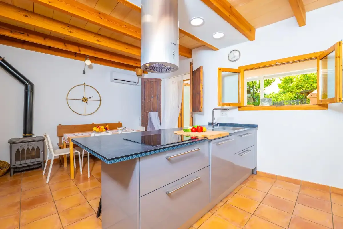 Una cocina luminosa con una isla central y vigas de madera en el techo.