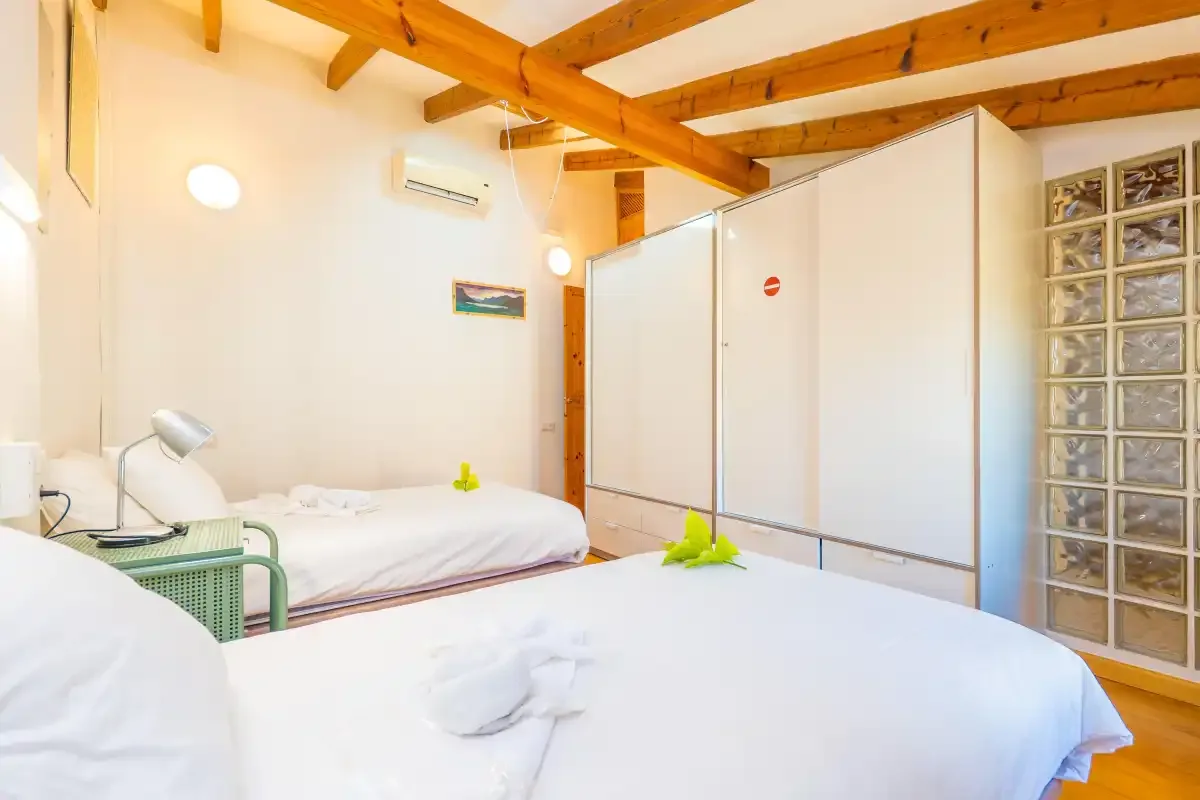 Un dormitorio con camas de ropa blanca y vigas de madera a la vista.