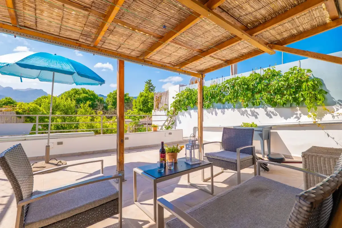 Una zona de estar al aire libre, bajo una pérgola, da a una terraza soleada.