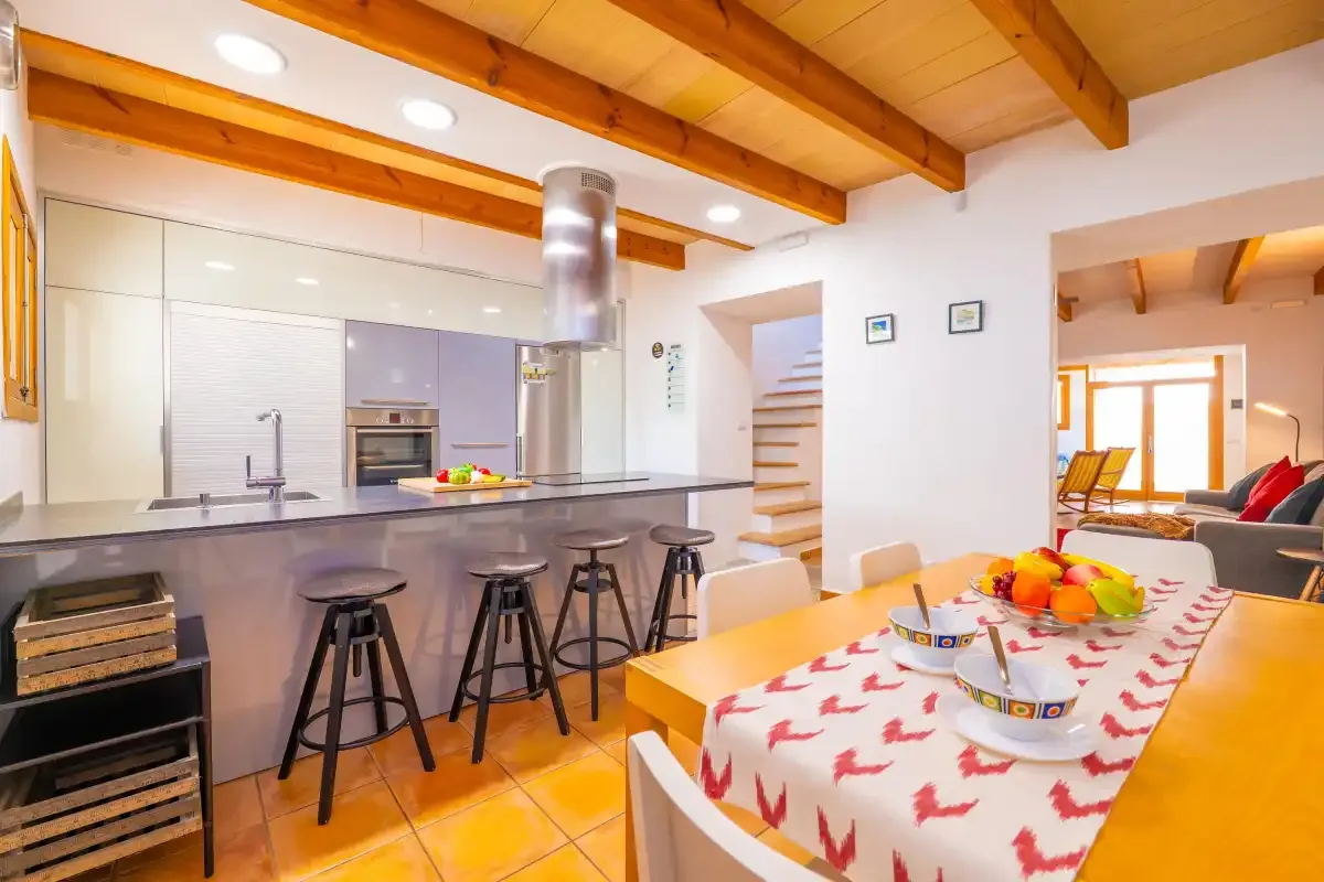Cocina y comedor con una barra, una mesa y vigas de madera vistas.