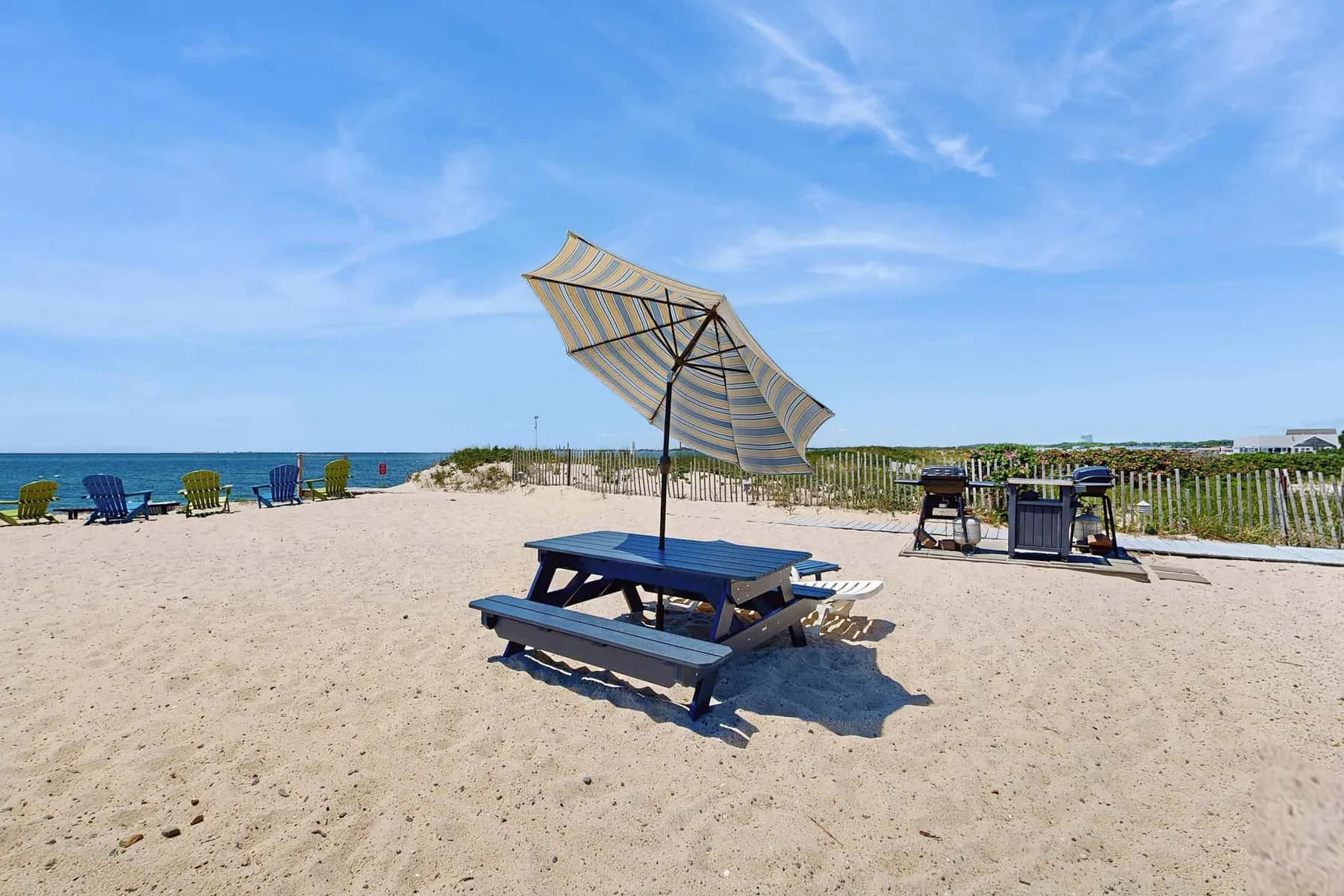 Una zona de picnic en la playa tiene una mesa sombreada frente al agua.