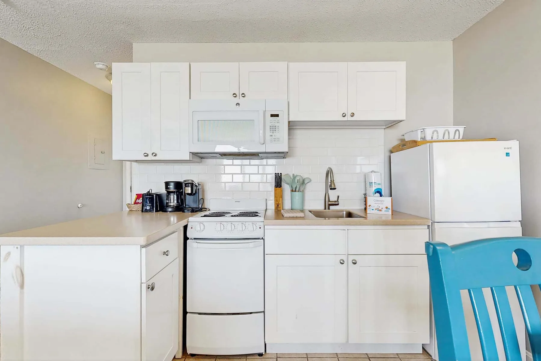 Una cocina luminosa con gabinetes blancos, una estufa y un refrigerador.