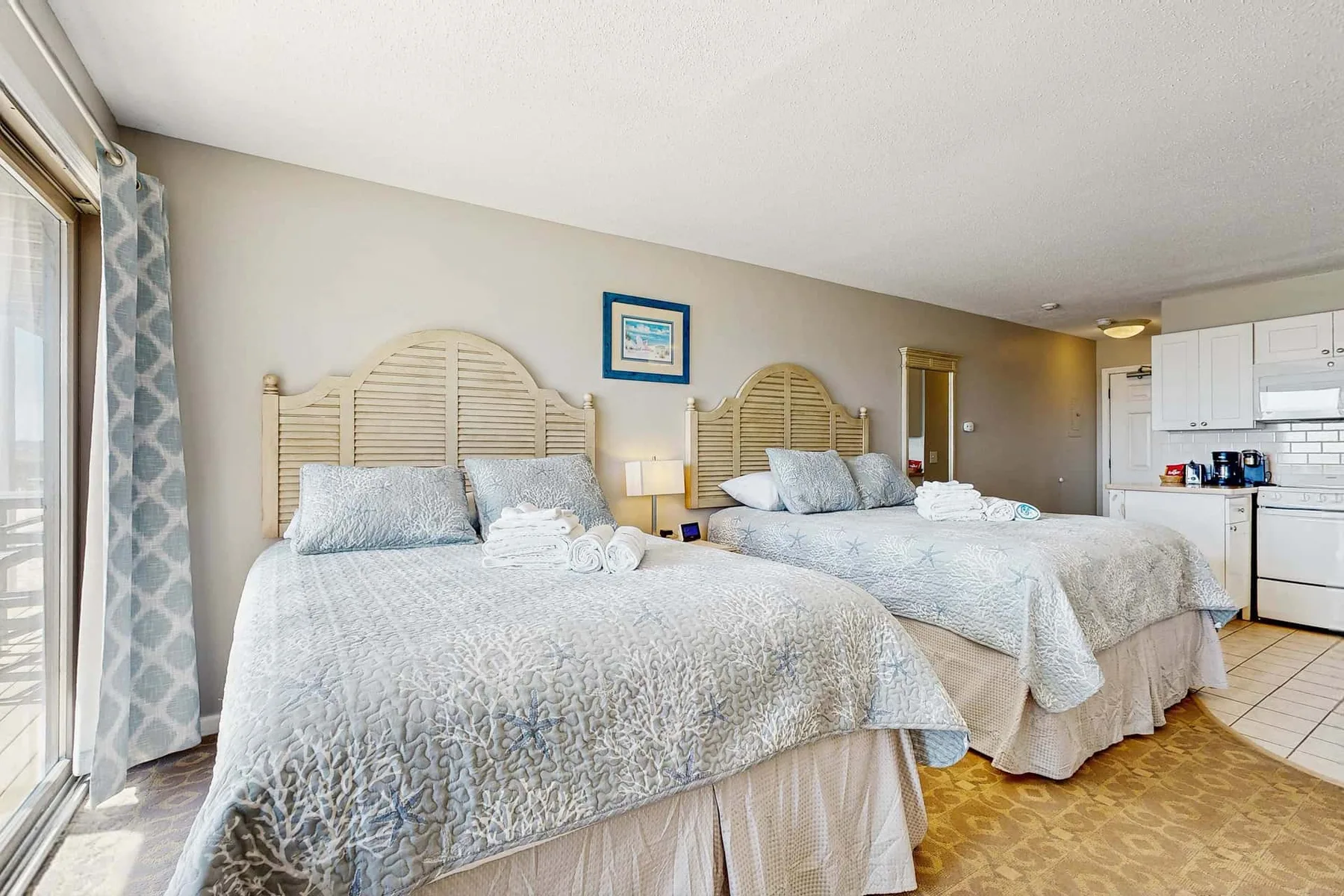 A bedroom with two beds, light bedding, and a window.
