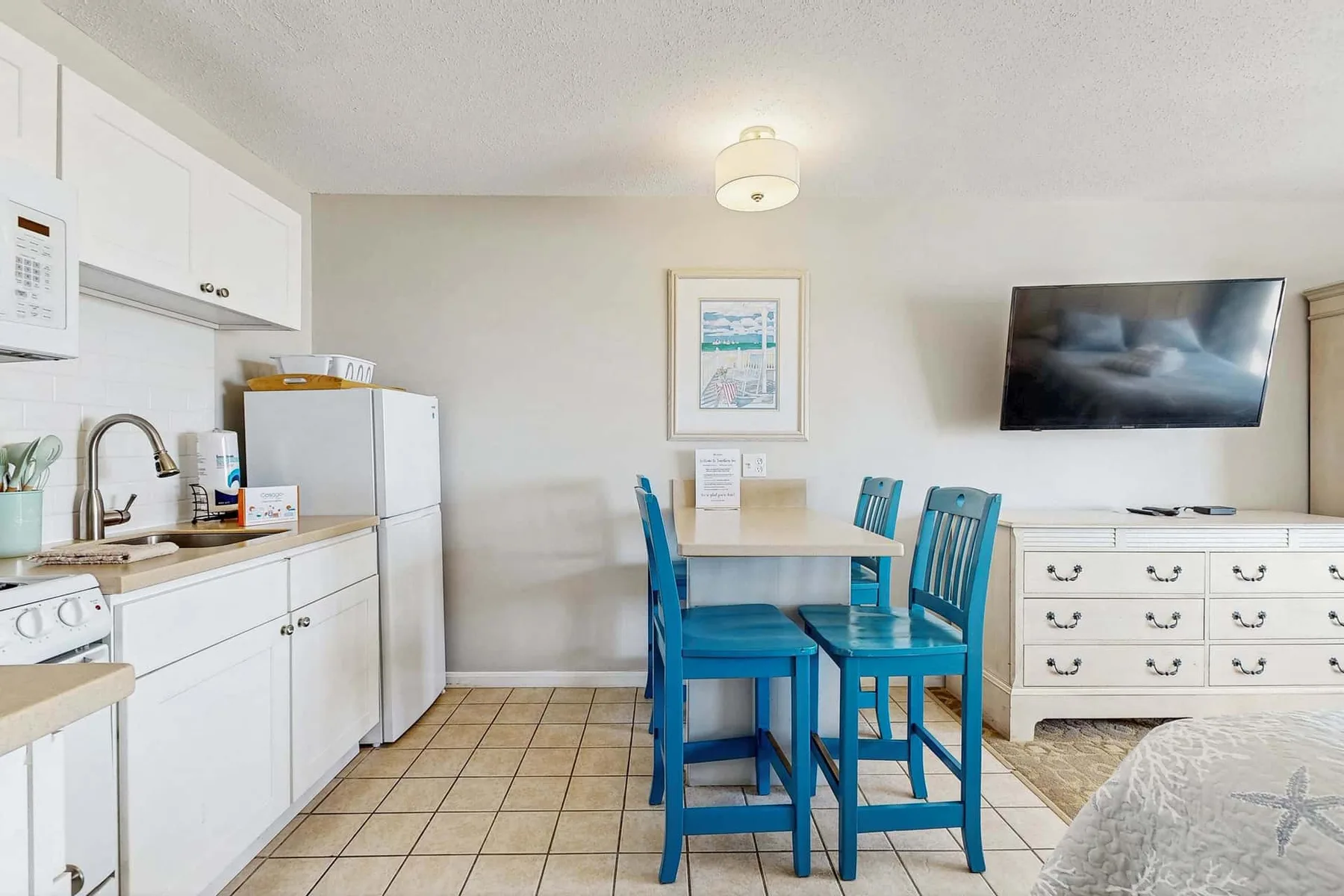 Una cocina compacta y zona de comedor con asientos azules alrededor de una mesa.