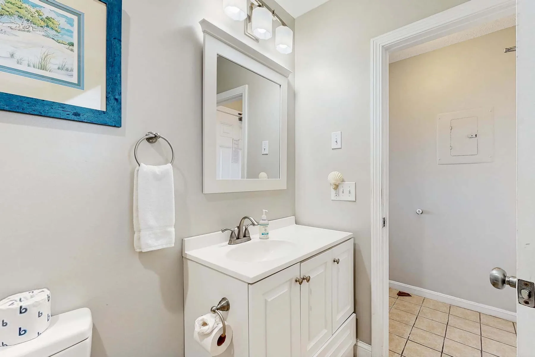Un baño luminoso con tocador blanco, espejo y puerta.