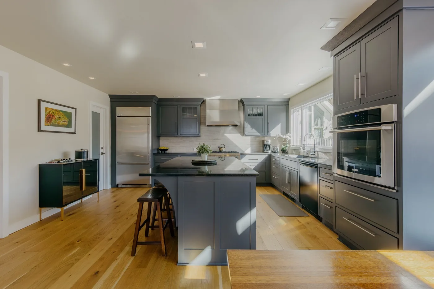 Una cocina amplia con gabinetes oscuros, una isla central y piso de madera.