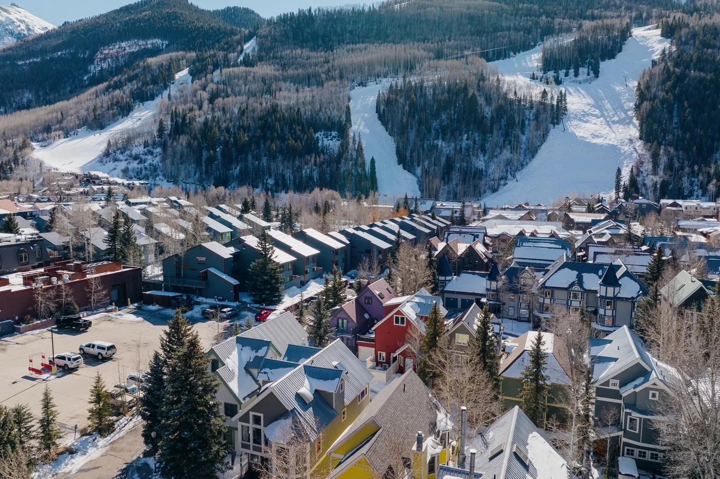 Un pueblo de montaña se encuentra bajo laderas boscosas cubiertas de nieve.