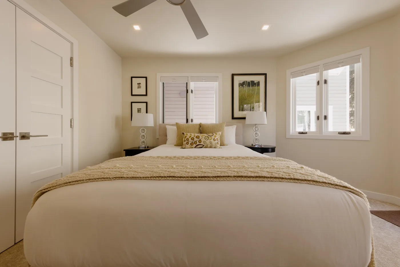 Un dormitorio con una cama tendida y ventanas detrás.