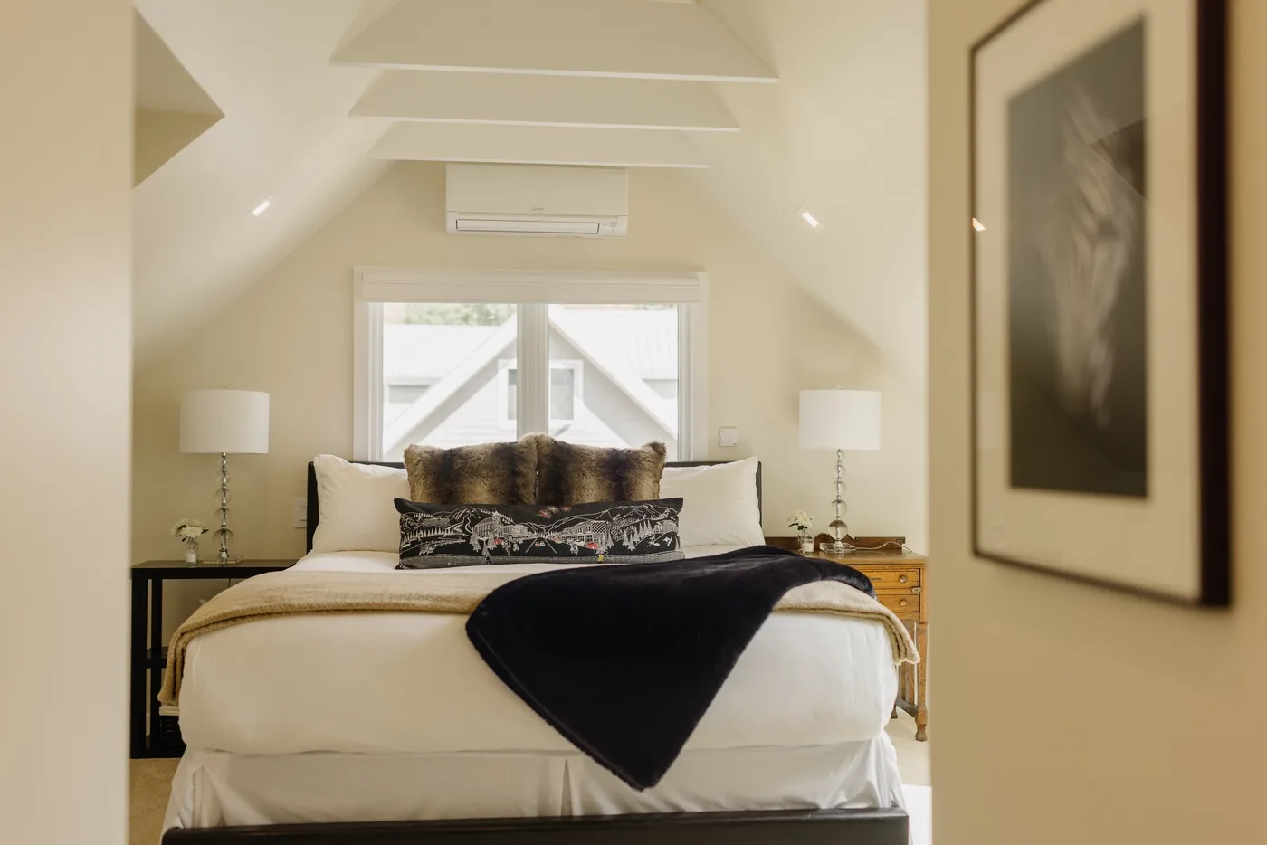 Un dormitorio con una cama bien tendida bajo un techo inclinado.