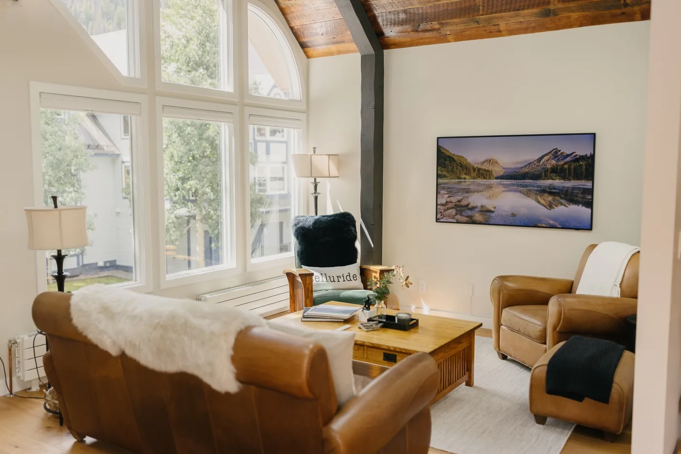 Una sala luminosa con asientos, grandes ventanas y un cuadro de paisaje enmarcado.