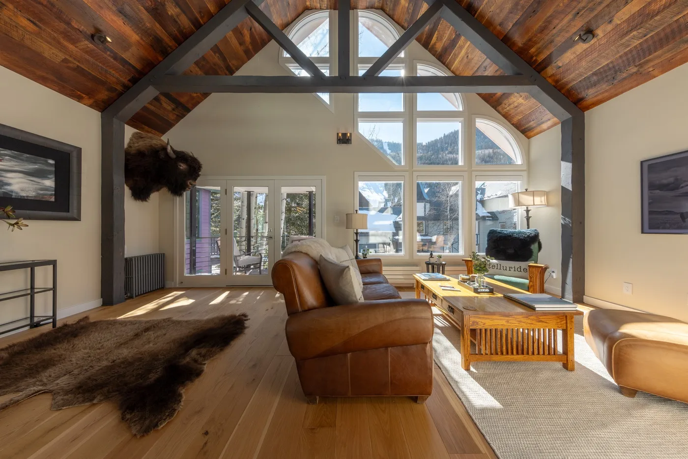 Una sala de estar abovedada con vigas de madera vistas y asientos alrededor de una mesa de centro.
