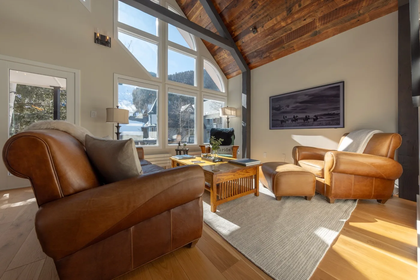 Una sala luminosa con asientos de cuero, grandes ventanas y un techo alto de madera.