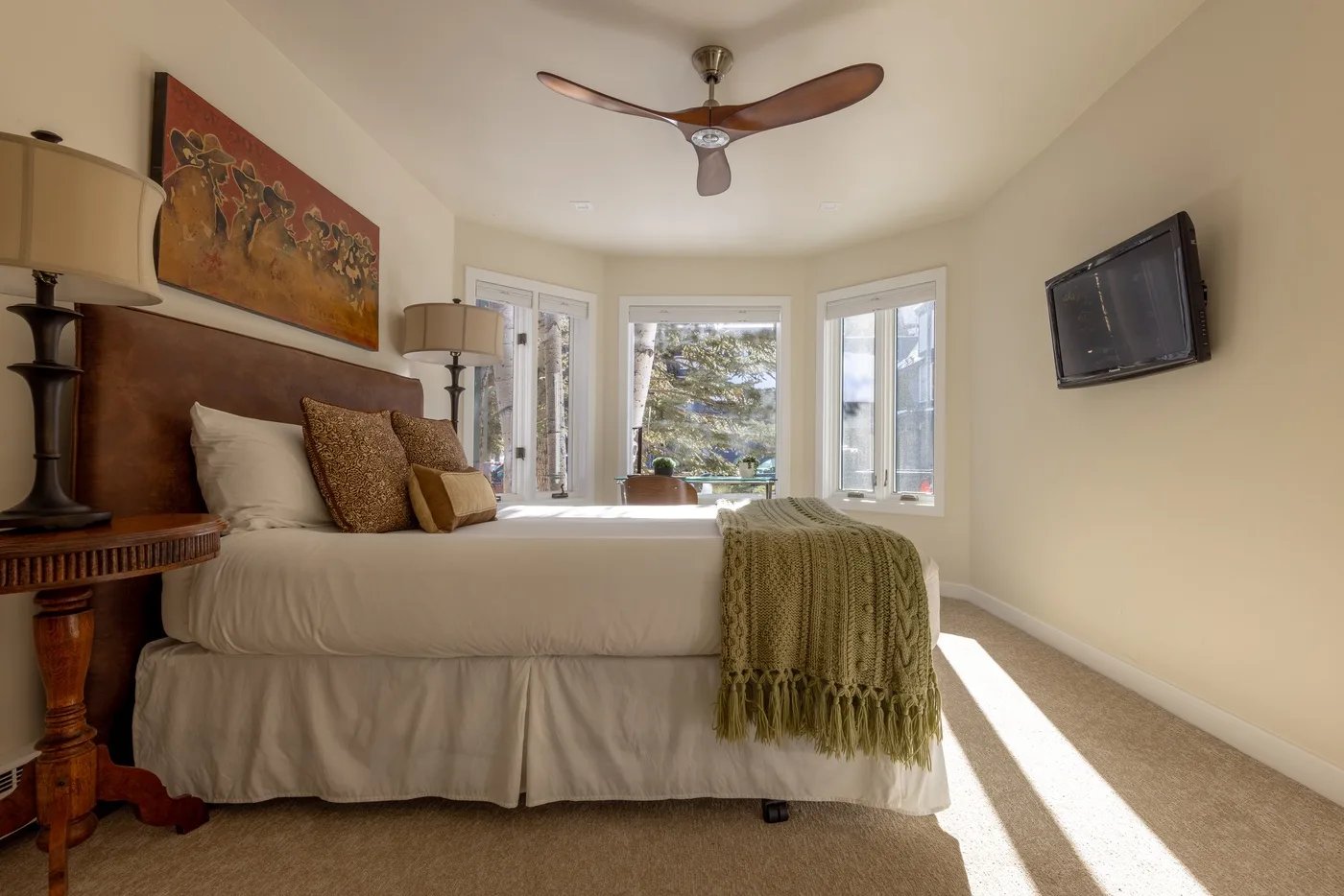 Un dormitorio con una cama junto a varias ventanas luminosas.