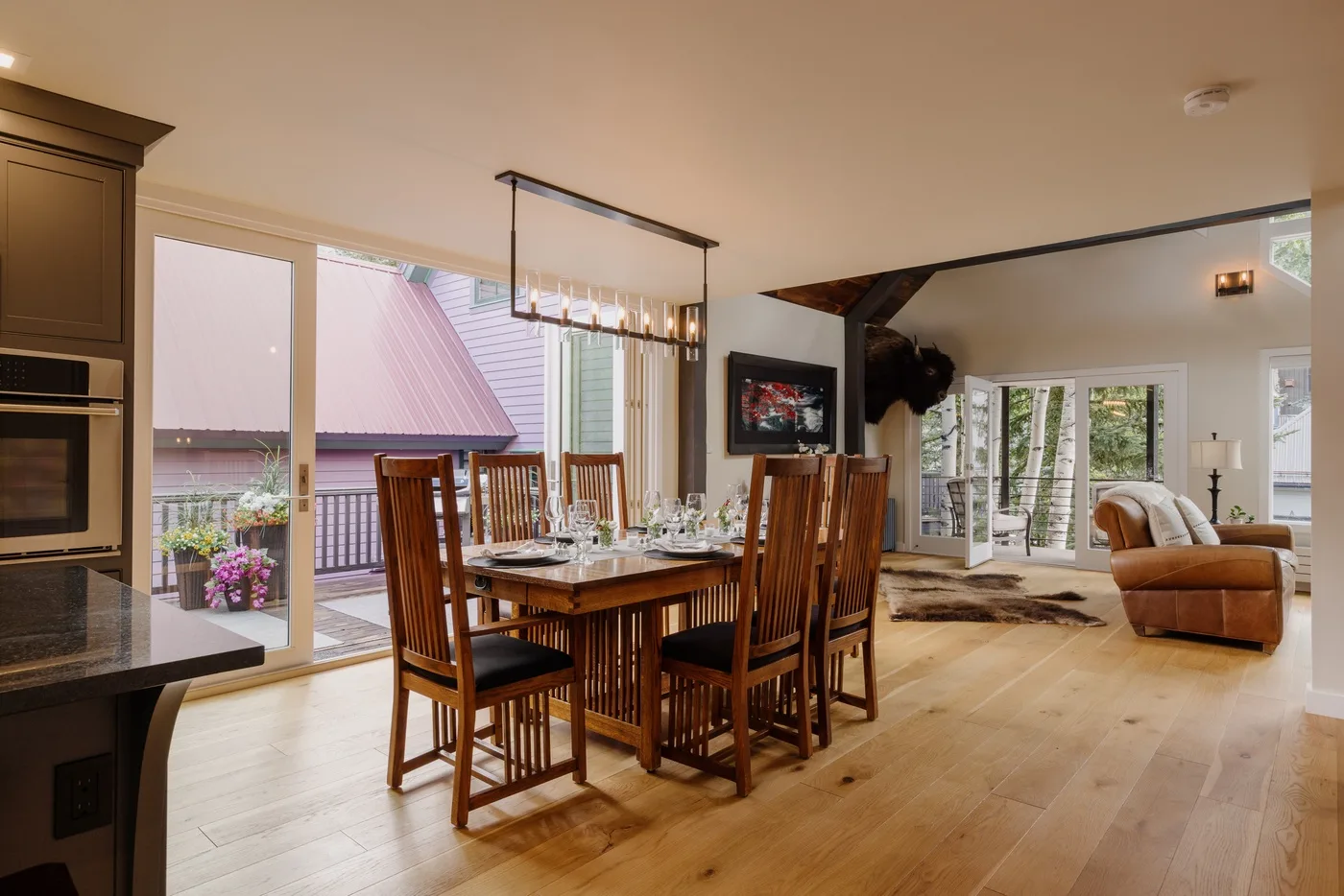 Comedor con una mesa de madera junto a grandes ventanales.