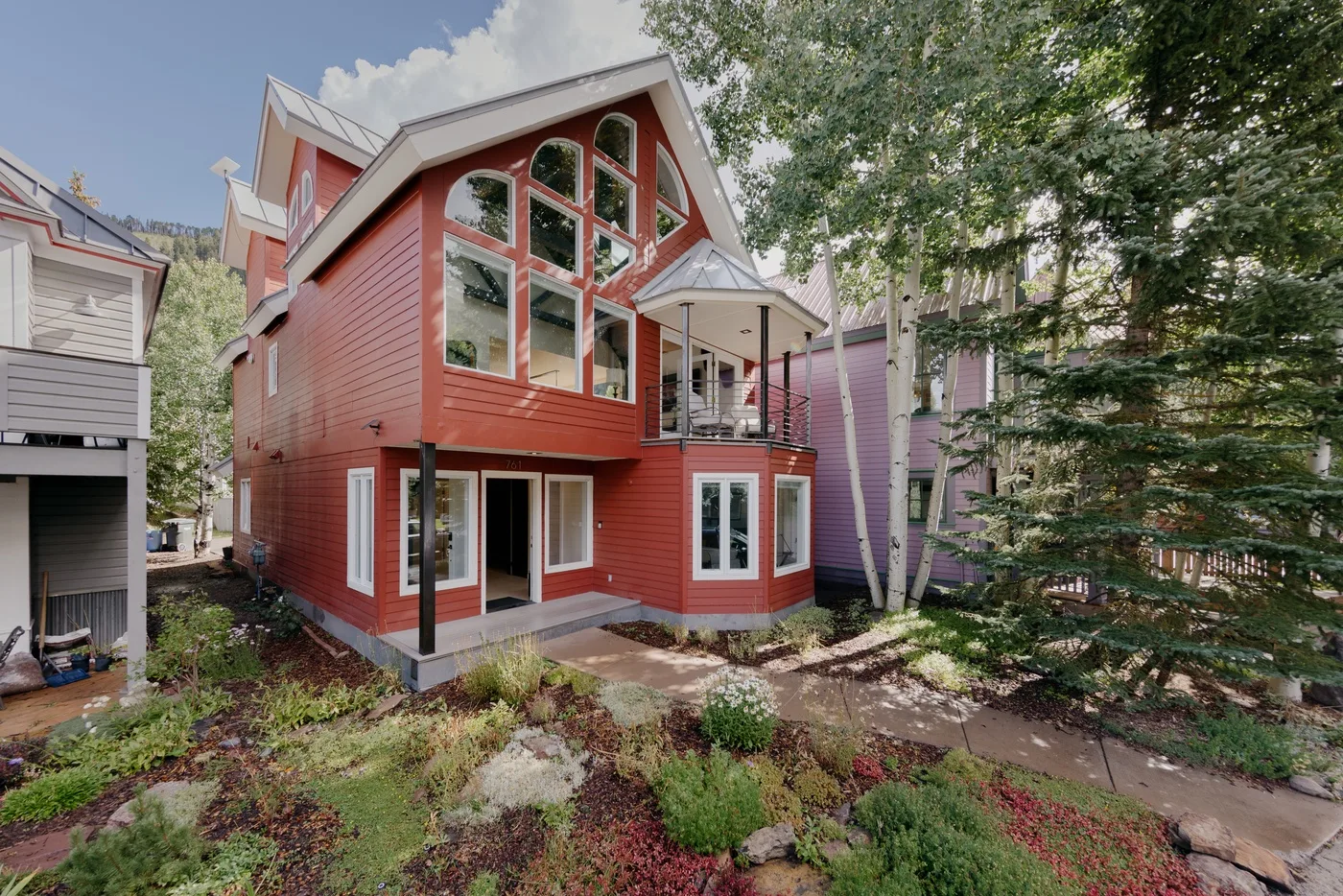 Una casa roja de varios pisos con grandes ventanas y un pequeño balcón cubierto.