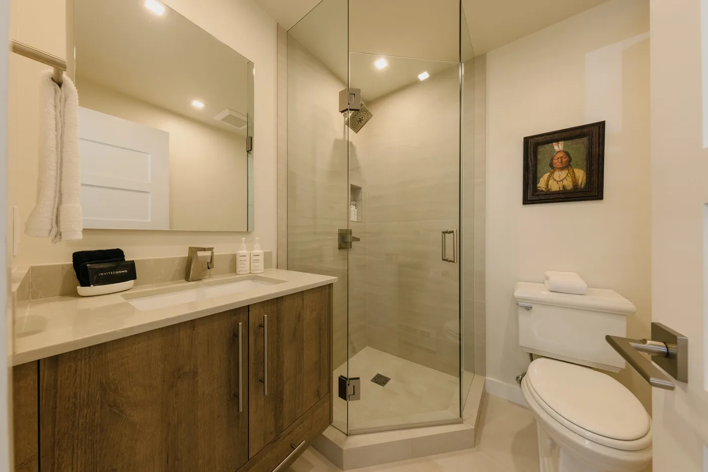 Un baño luminoso con lavabo, ducha de vidrio e inodoro.