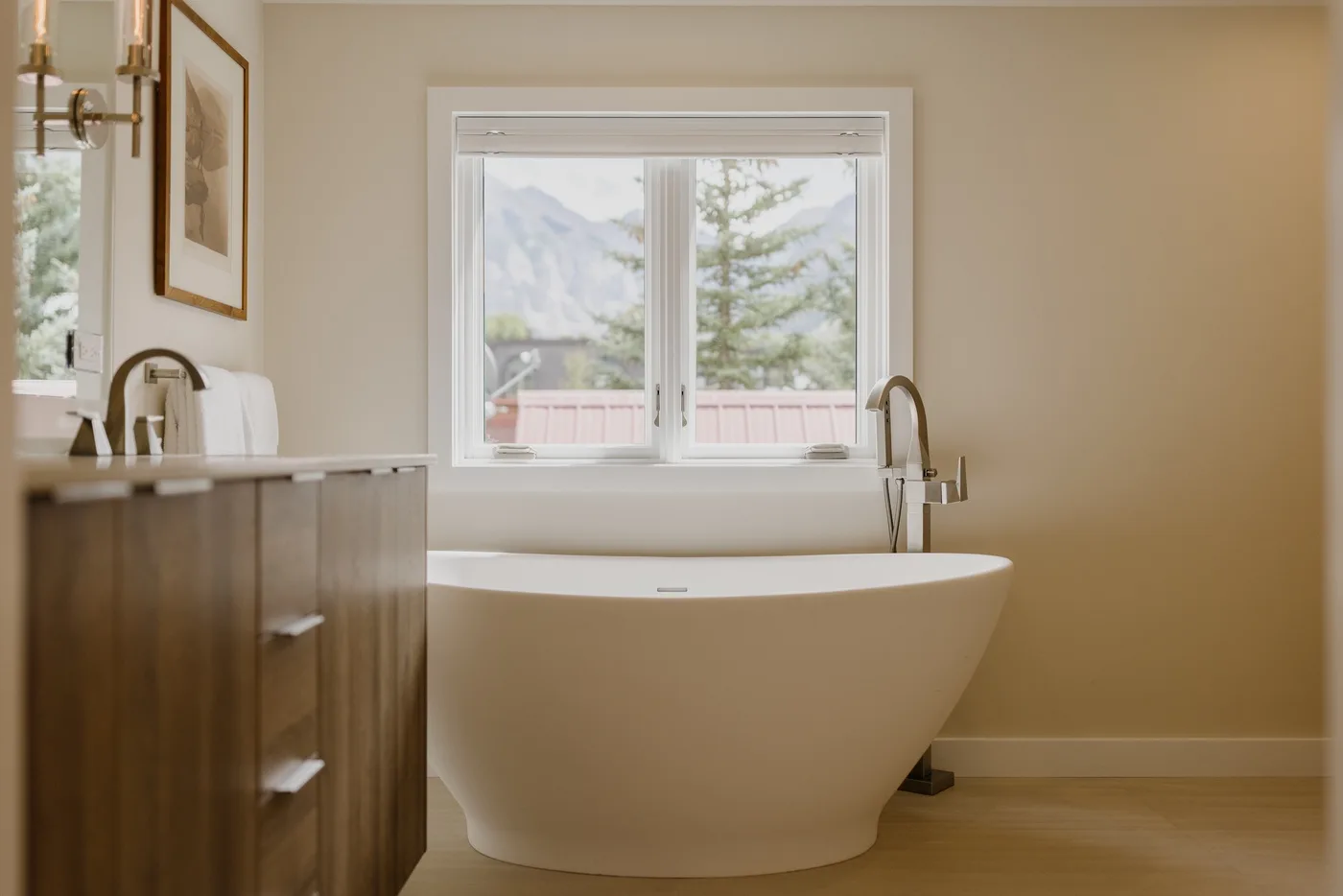 Un baño con una bañera independiente bajo una ventana.