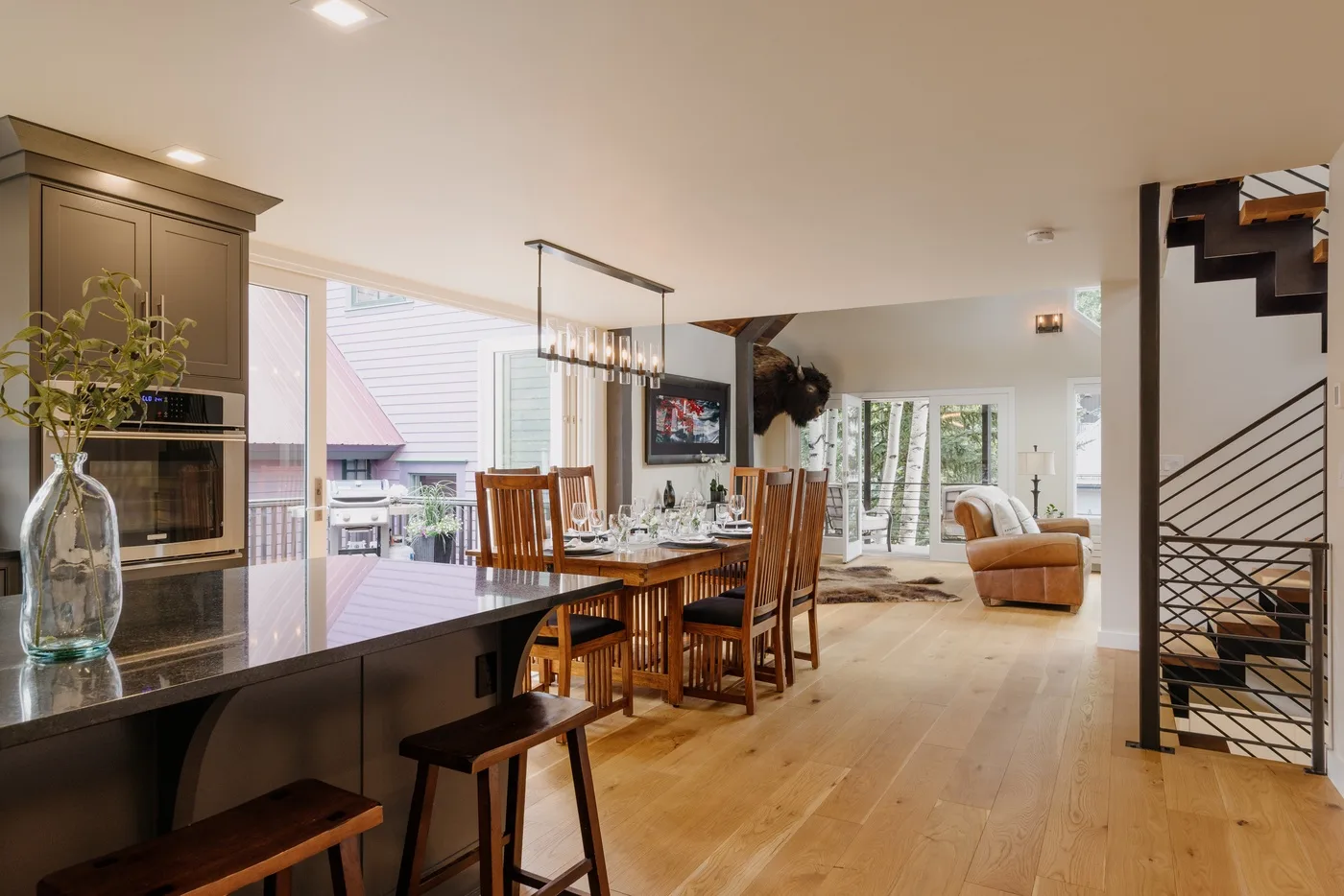 Una cocina y comedor de planta abierta dan a una sala de estar con sofá y grandes ventanas.