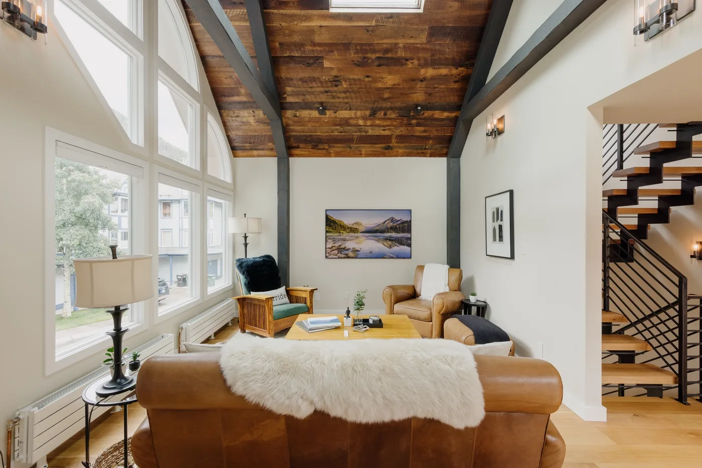 Una sala luminosa con grandes ventanas, asientos de cuero y techo de madera.