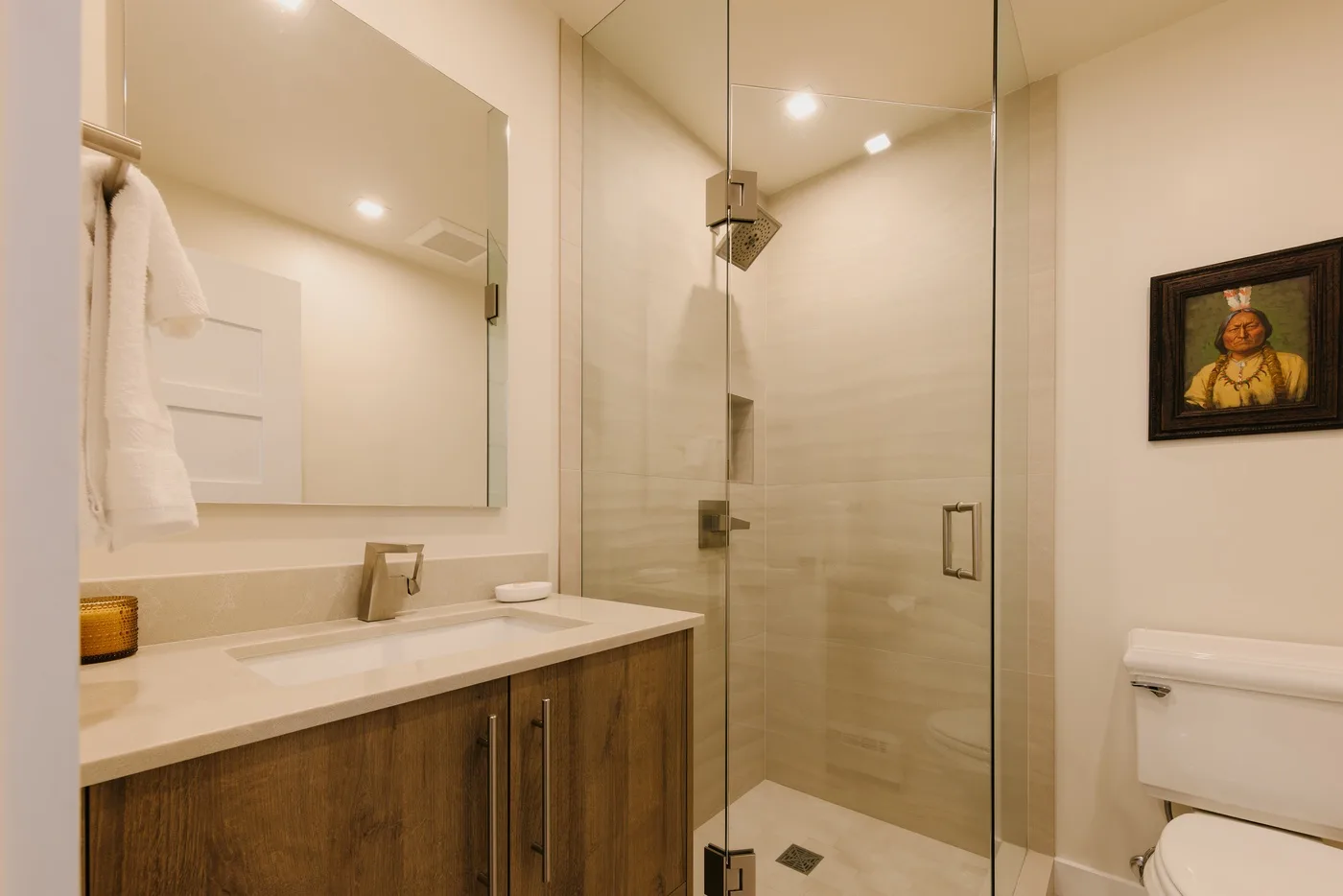 Un baño luminoso con lavabo, ducha de vidrio e inodoro.