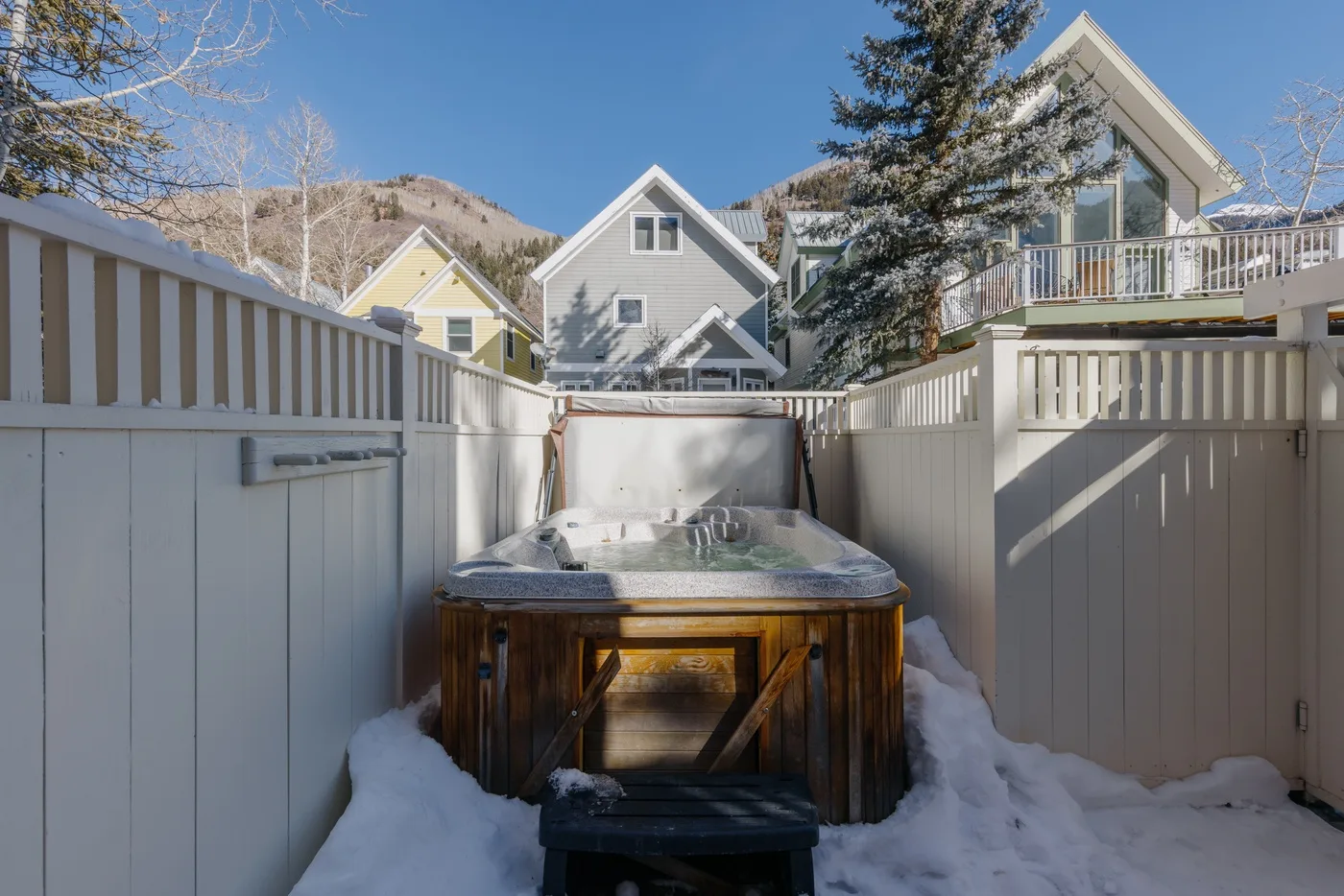 Una bañera de hidromasaje al aire libre está en un área cercada y rodeada de nieve.