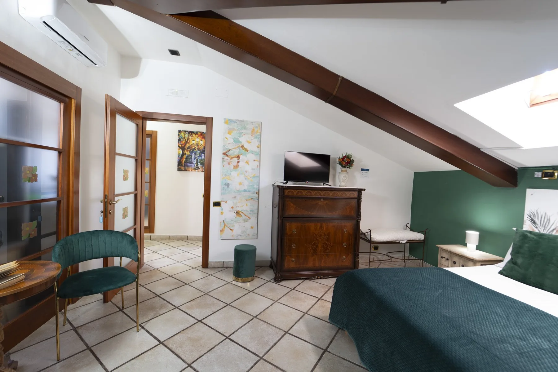 A bedroom with a bed, dark wooden dresser, and green accent wall.