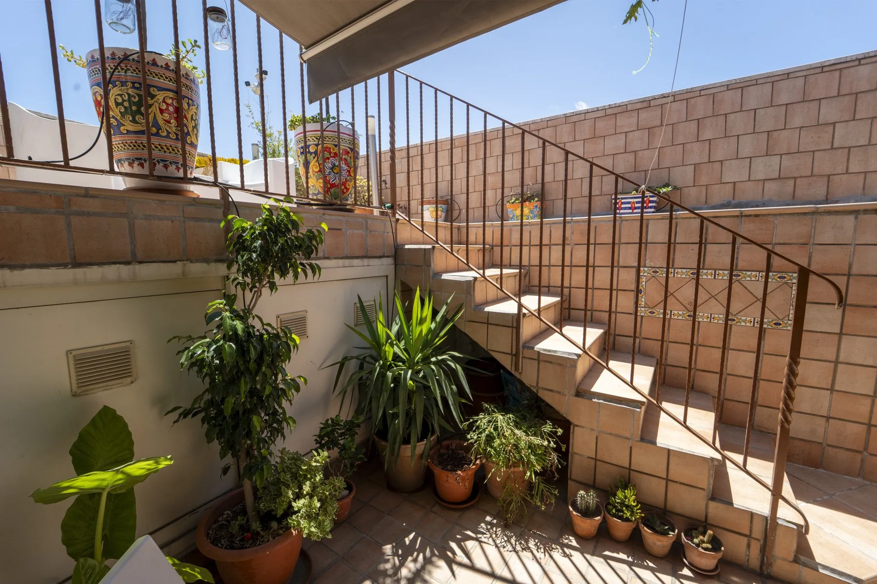 An outdoor tiled stairway with metal railings and potted plants.