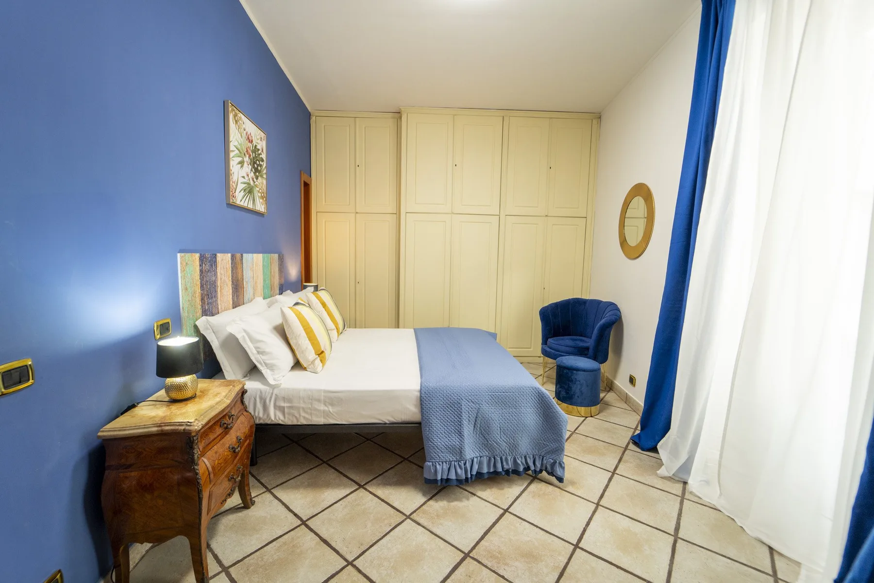 A bedroom with a bed, built-in wardrobes, and a blue armchair.