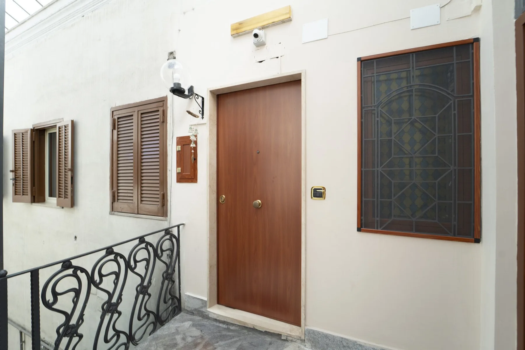 A white-walled corridor with a wooden door and decorative metal railing.
