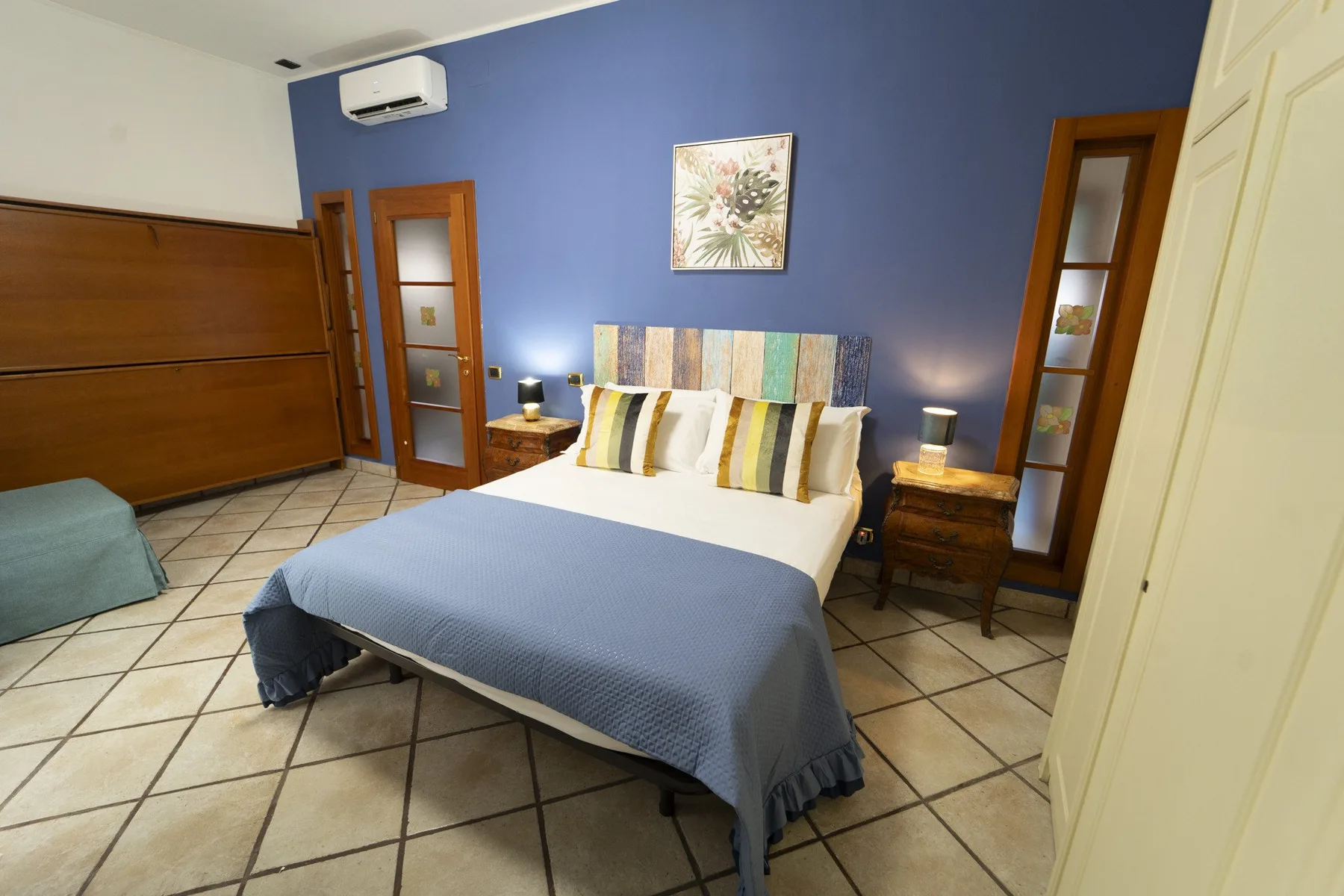 A bedroom with a bed, bedside tables, and blue walls.