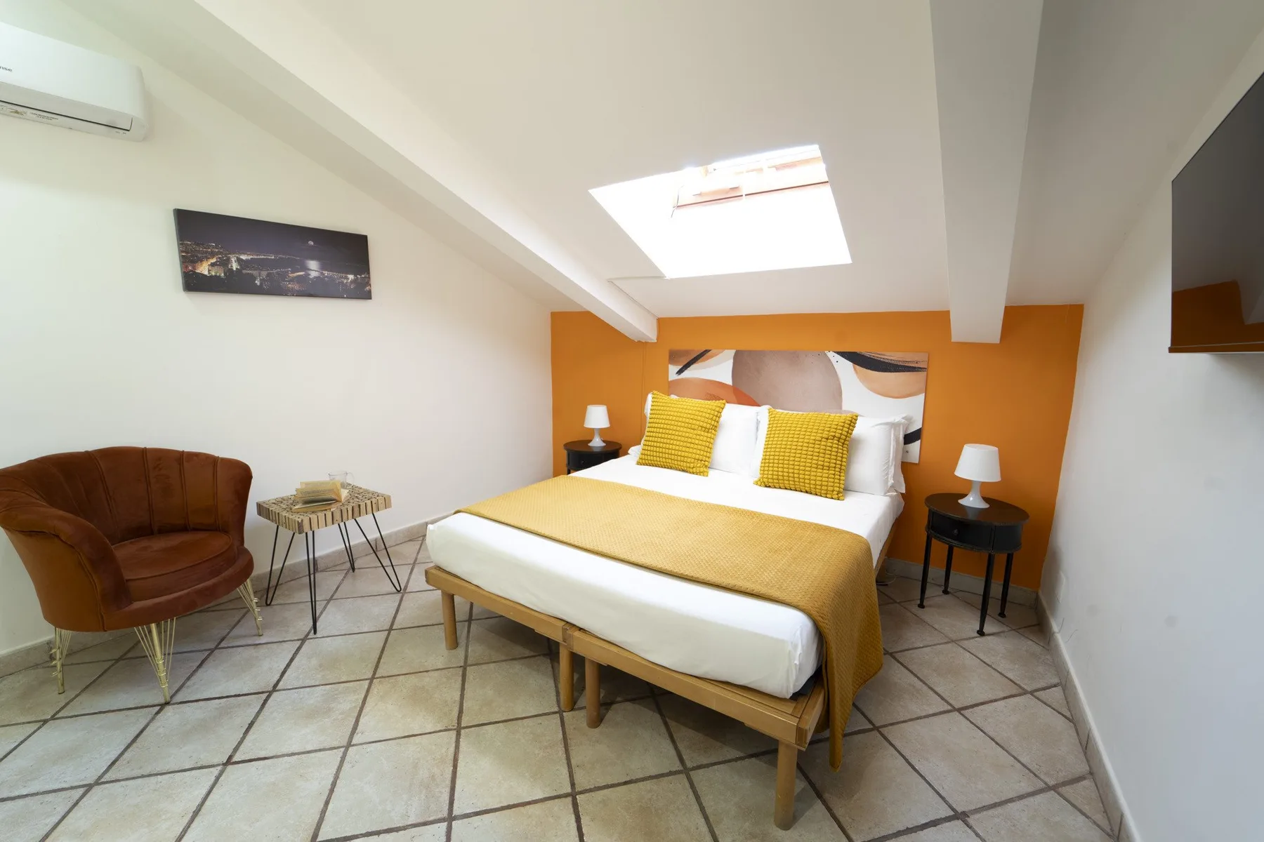 A bedroom with a bed dressed in white and mustard yellow bedding.