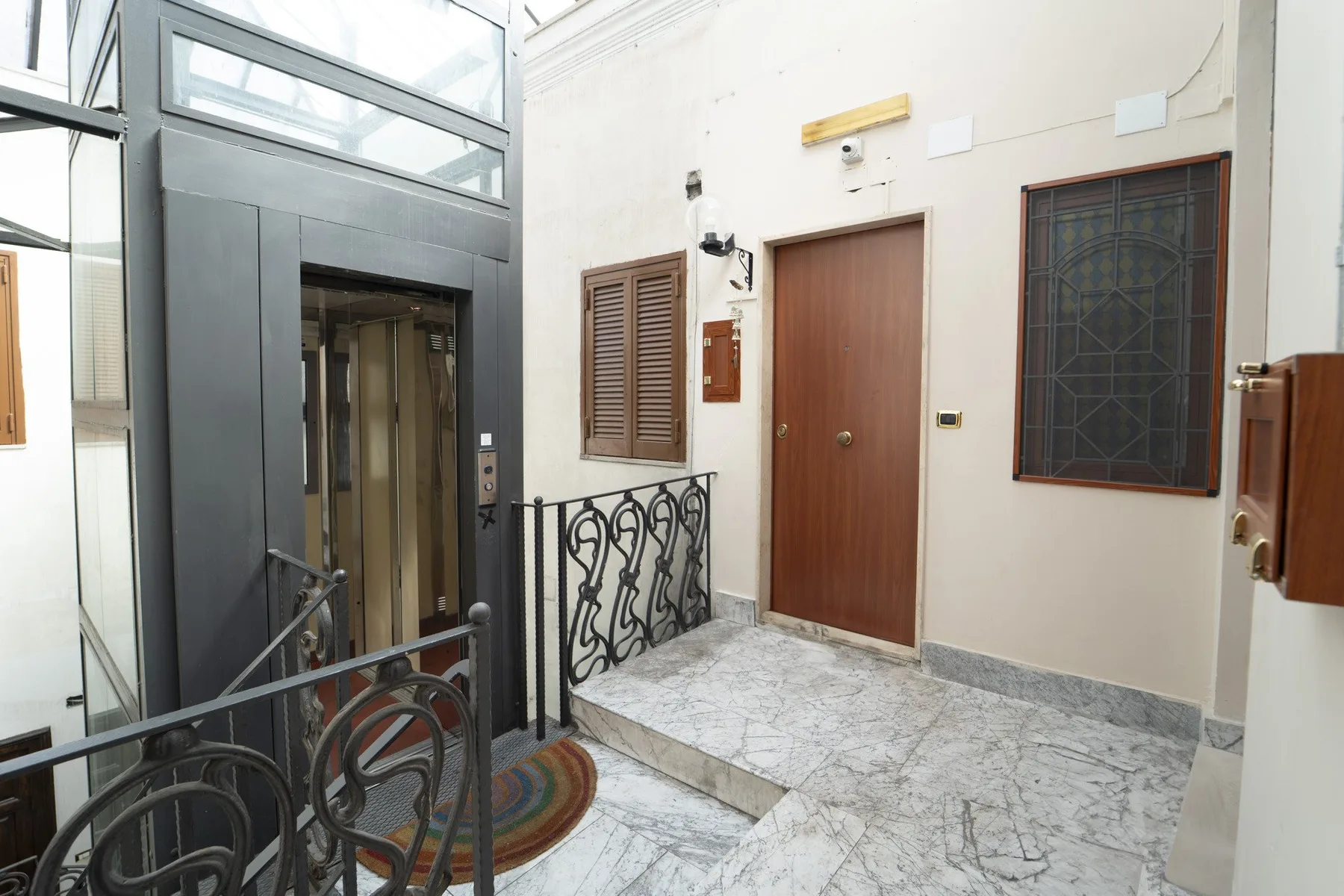 A building entrance hall with an elevator and a wooden door.