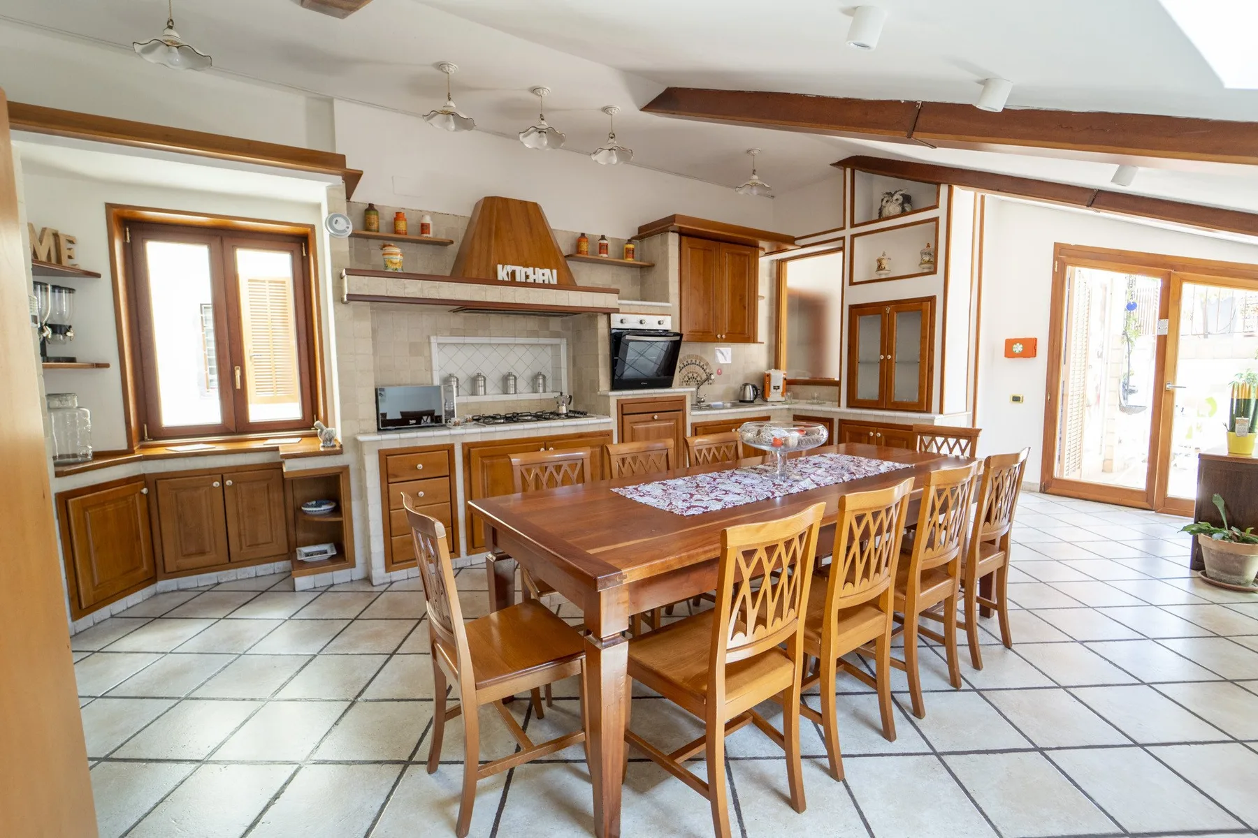 A spacious dining area with a long wooden table and built-in kitchen cabinetry.