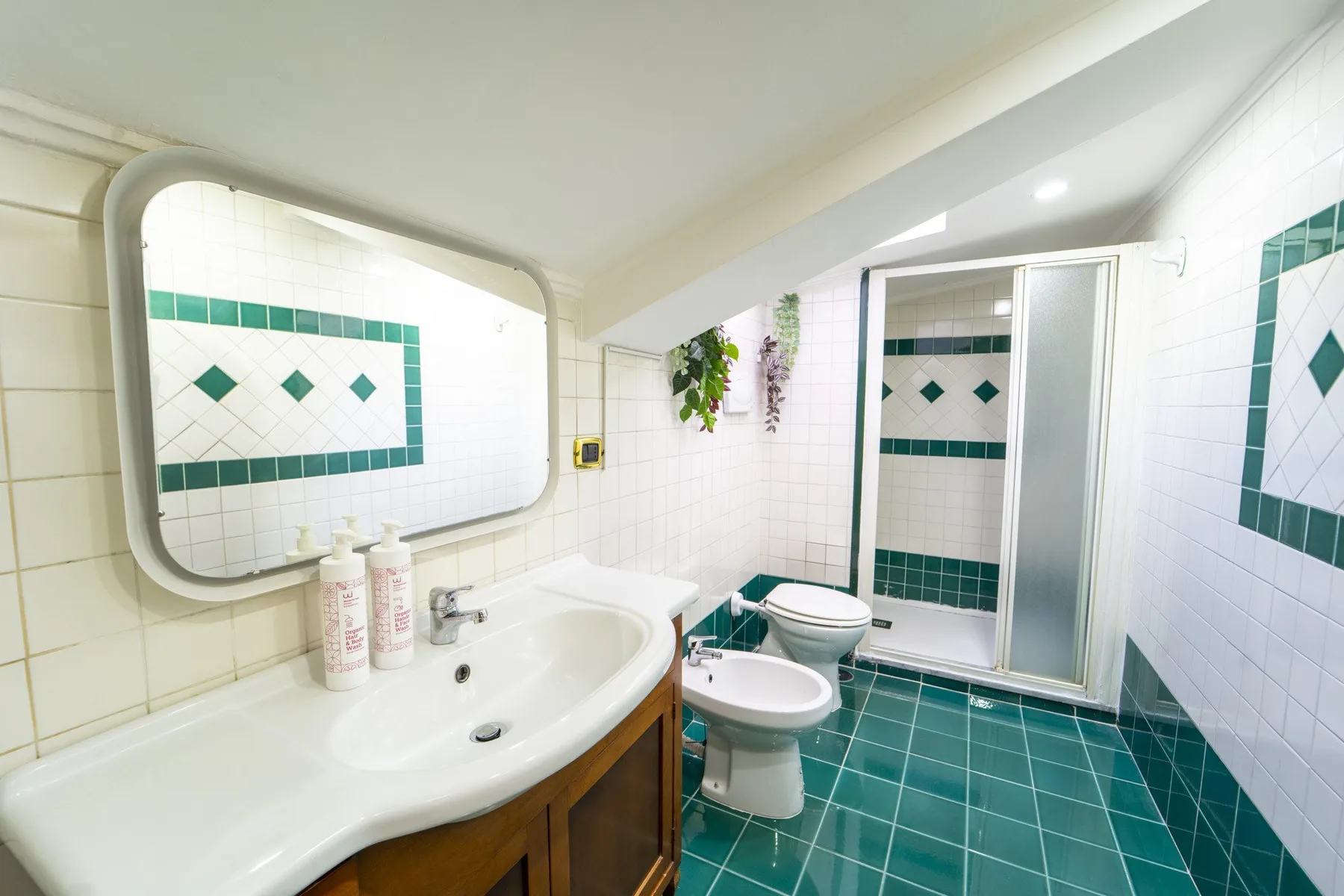 A tiled bathroom with a sink, toilet, bidet, and shower.