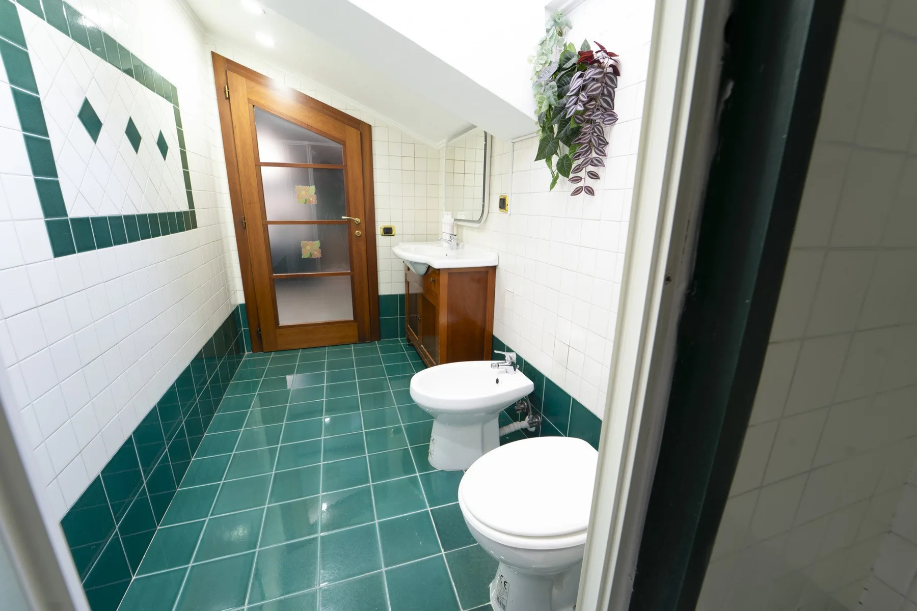 A tiled bathroom with a sink, toilet, and wooden door.