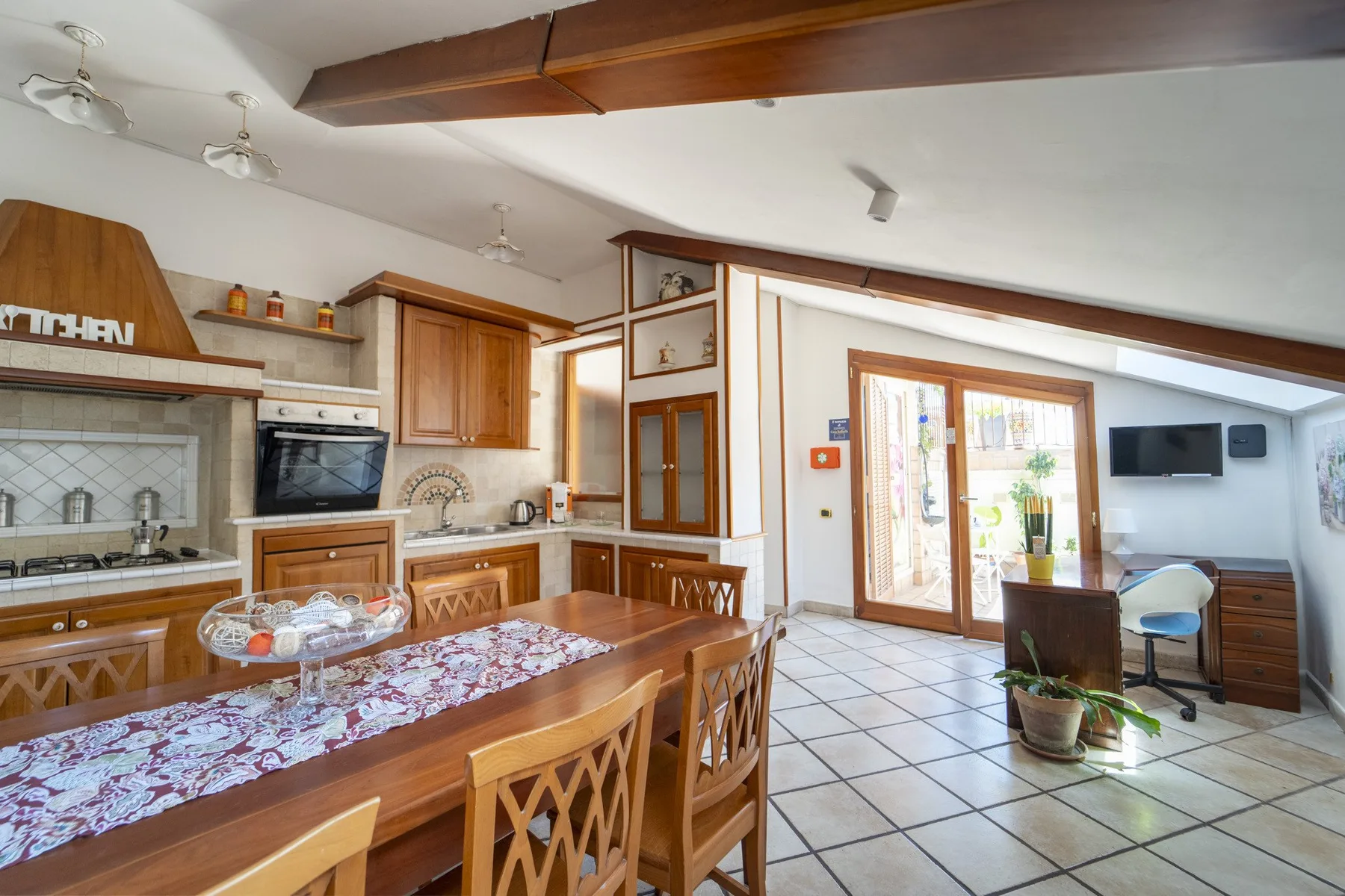 A dining area beside a kitchen, with a wooden table and chairs.