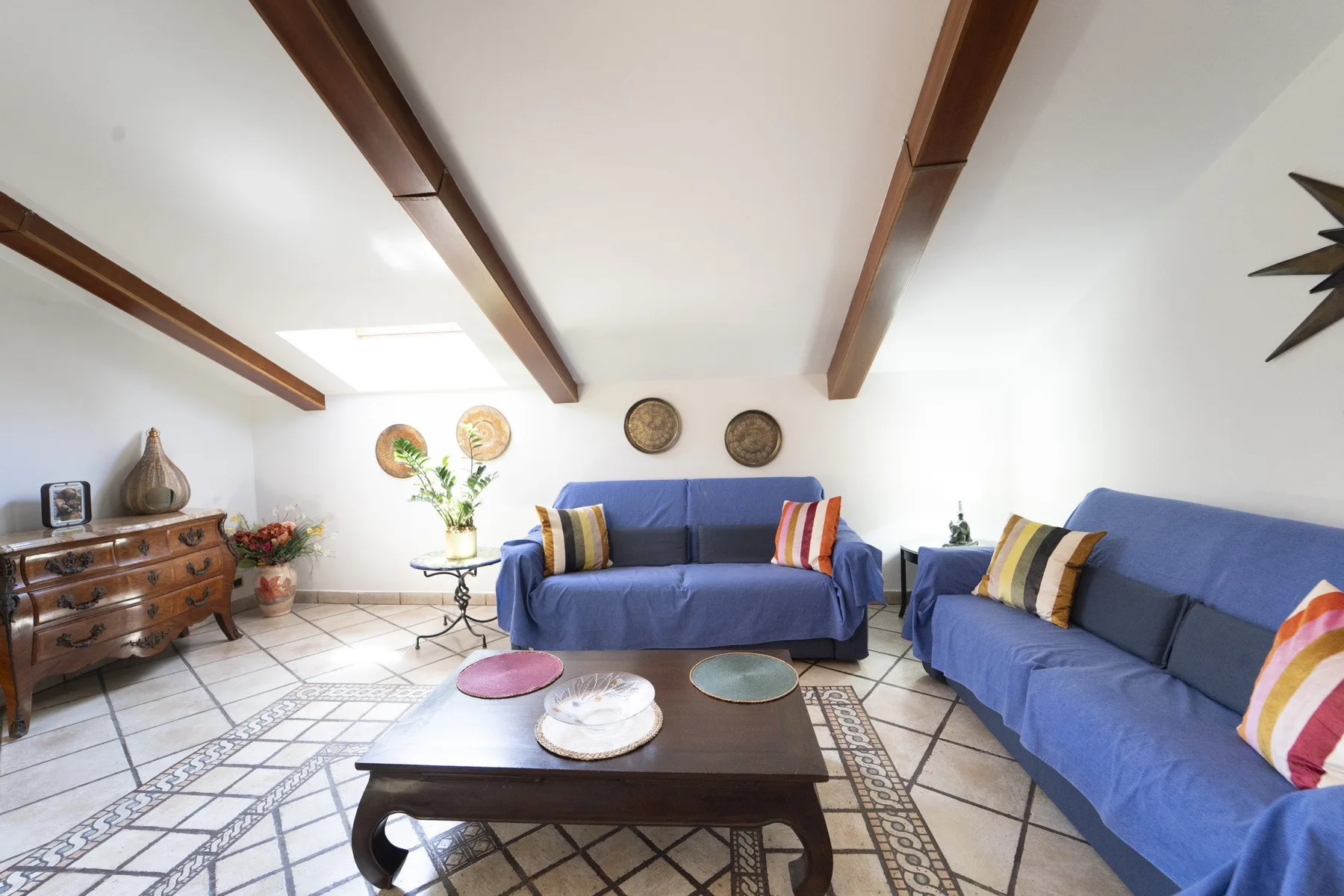 A bright living room with blue-covered seating and a low coffee table.