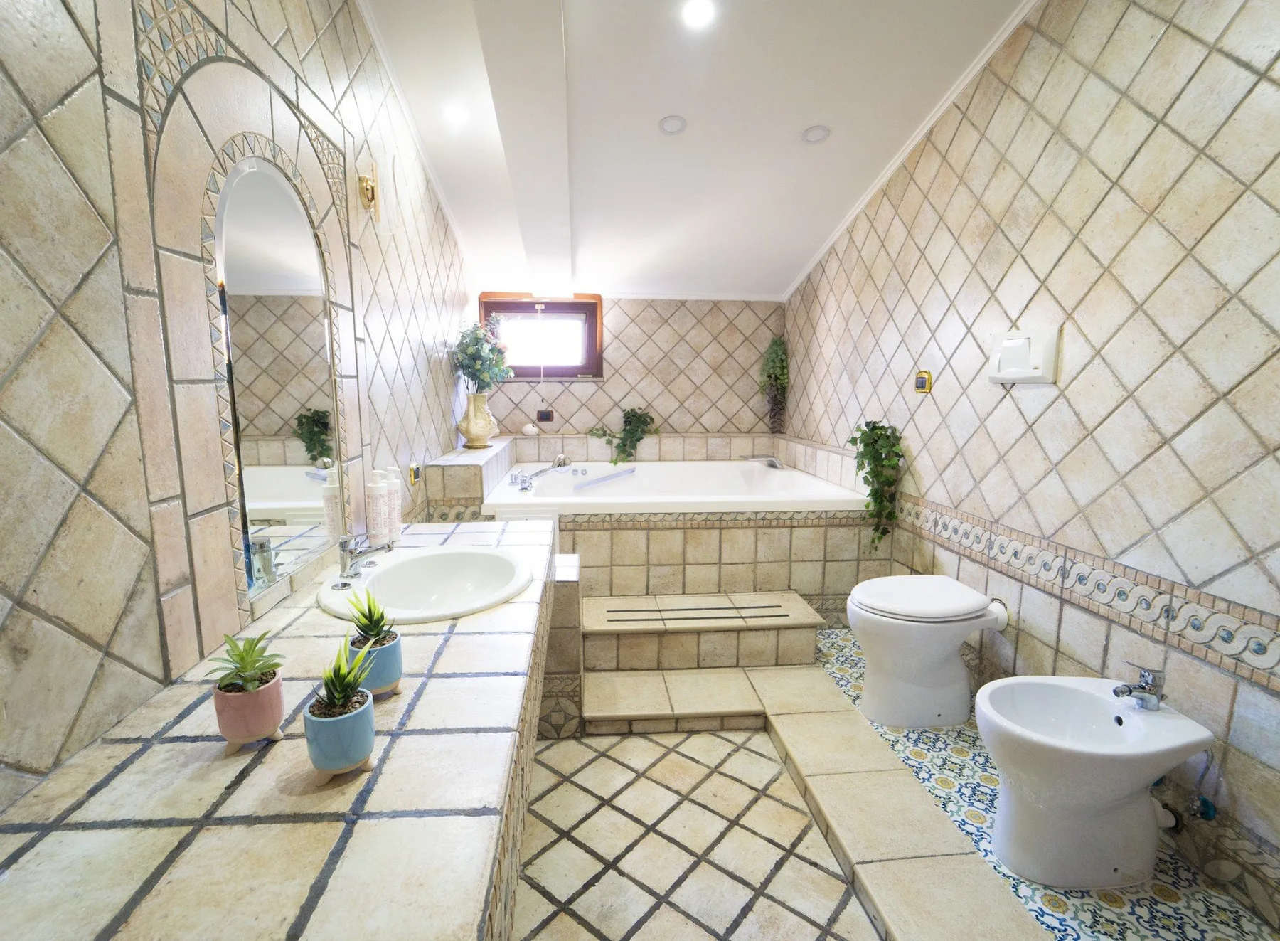 A tiled bathroom with a bathtub, sink, and toilet.