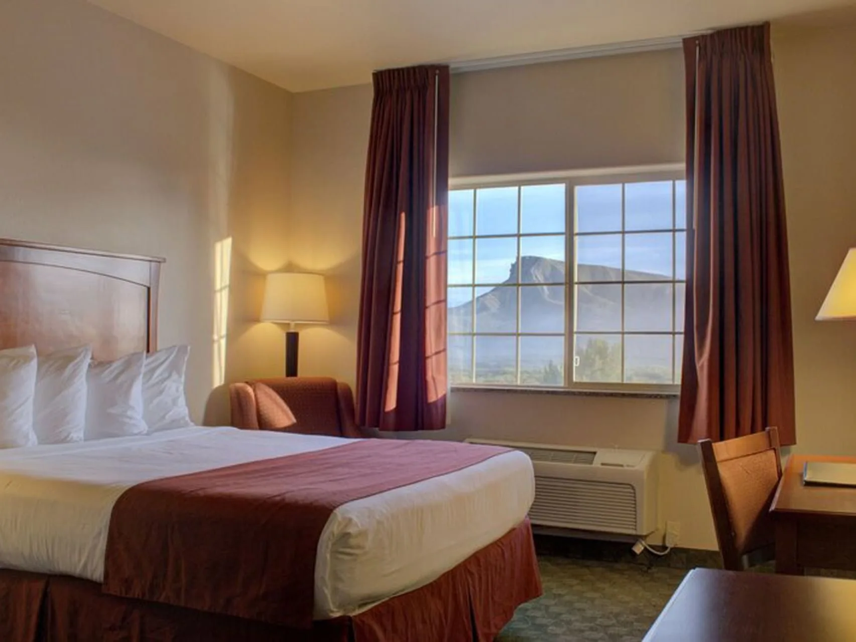 Habitación con dos camas queen, una cama y una zona de estar junto a la ventana con vistas a la montaña.