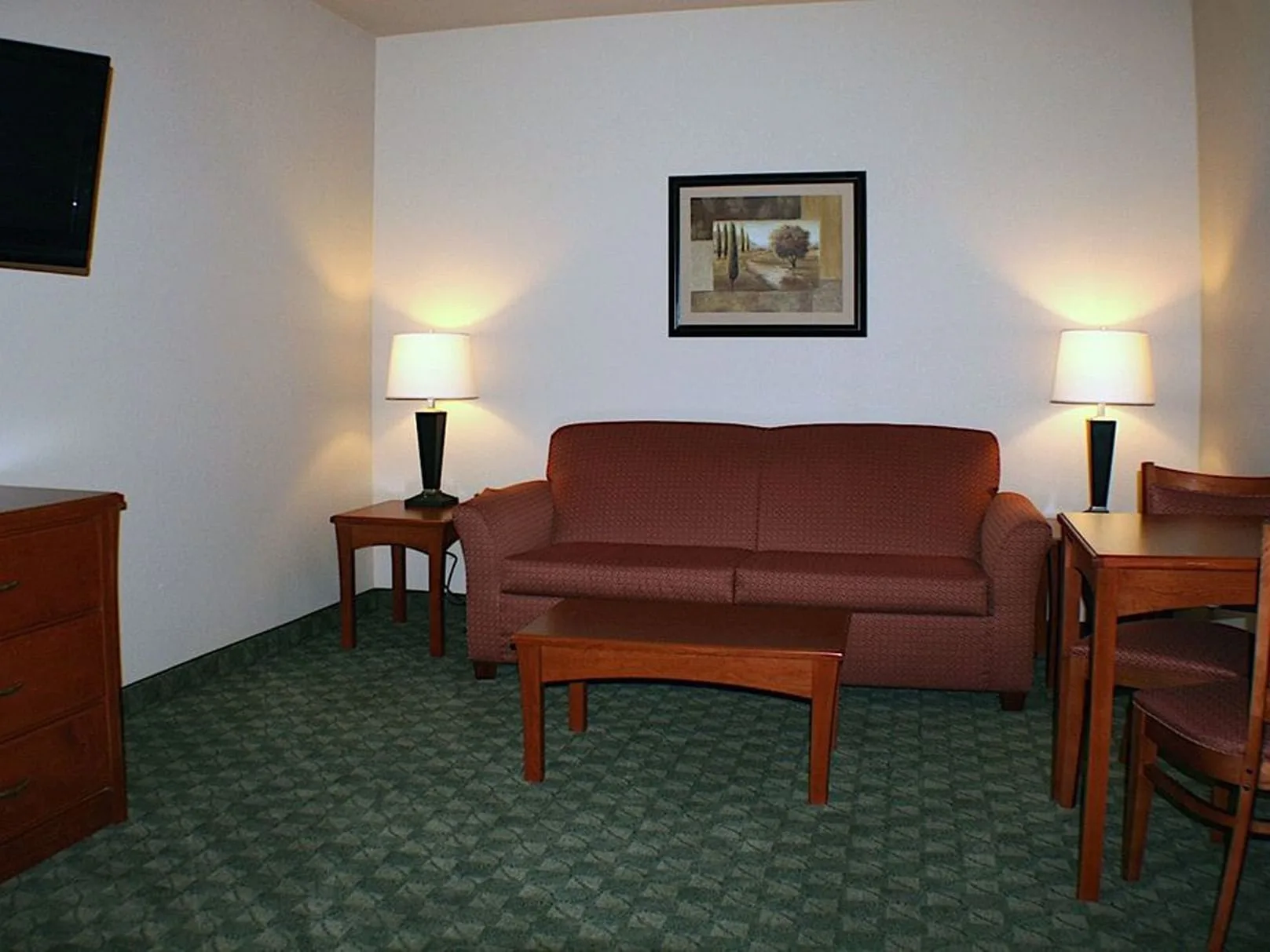 Sala de estar de la suite con vistas al acantilado, con un sofá rojo, una mesa de centro y una mesa de comedor.