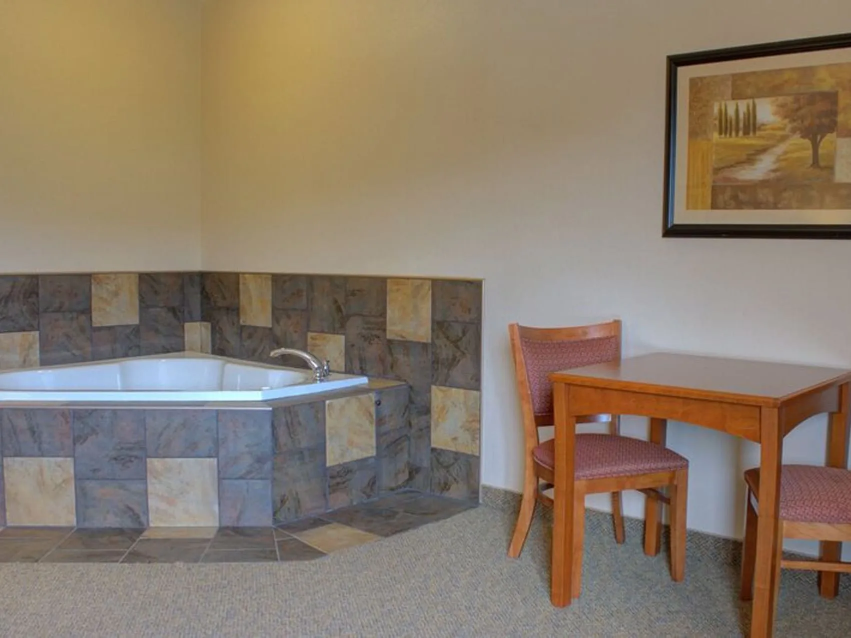 Suite con jacuzzi y vistas al acantilado, con una bañera de hidromasaje revestida de azulejos y una mesa de comedor de madera.