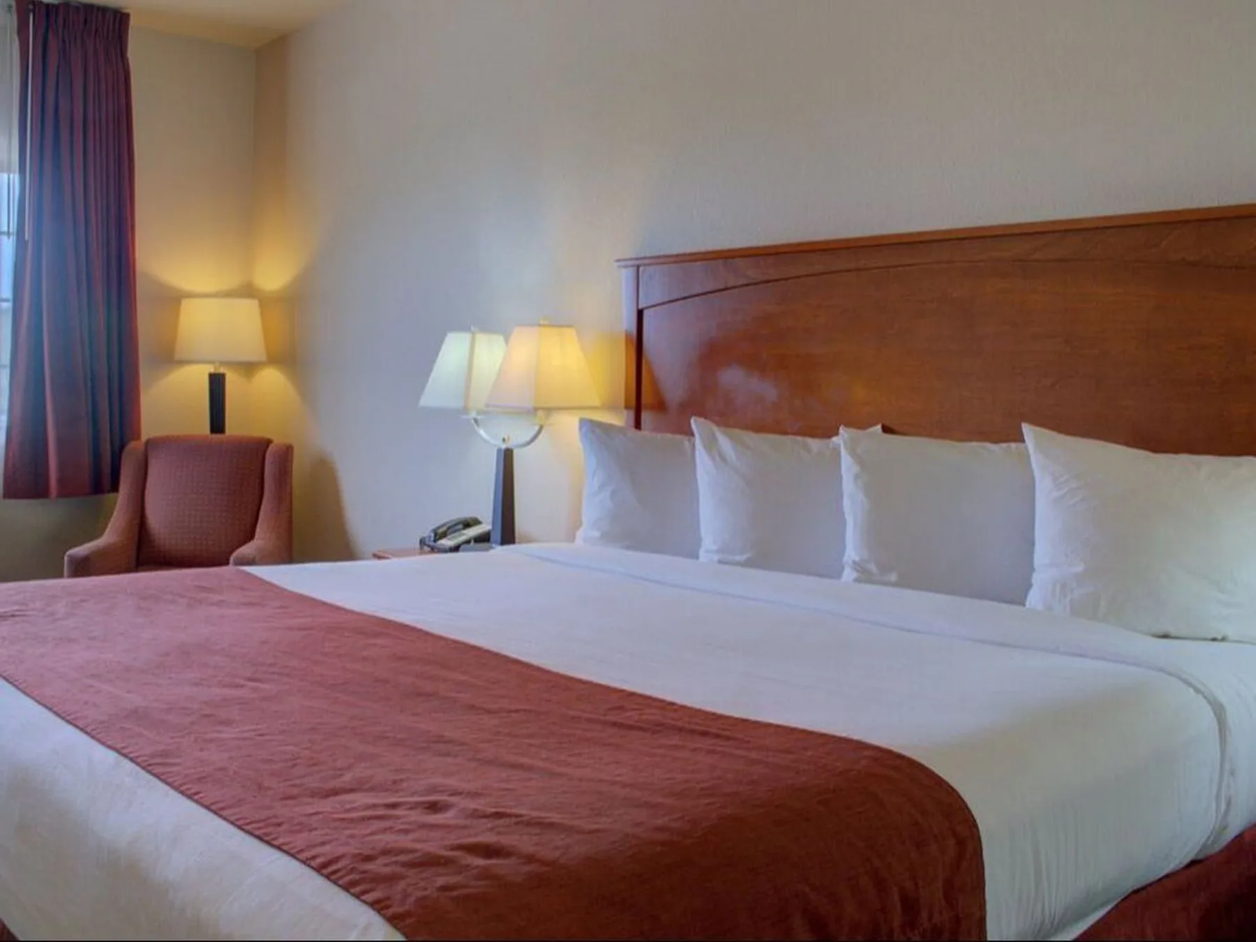 Habitación con cama king, una silla y lámparas.